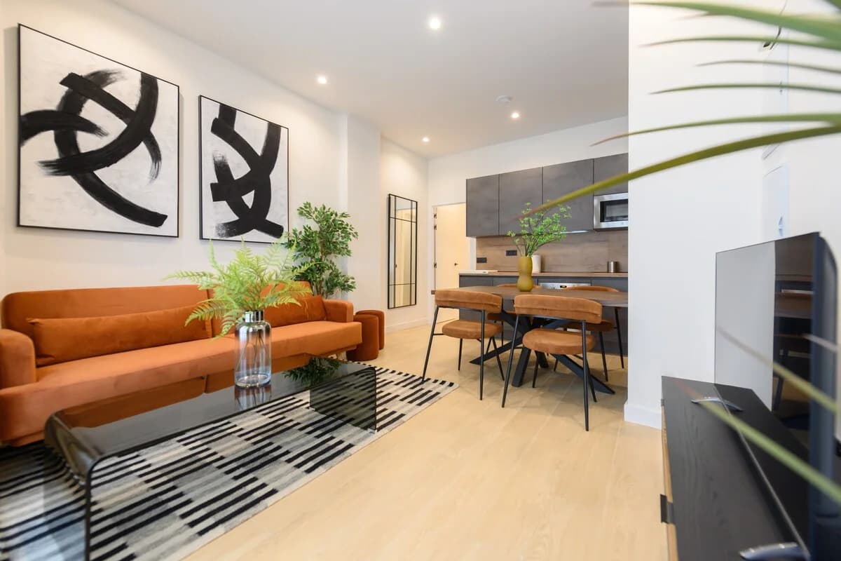Wide open-plan living-dining-kitchen with rust velvet sofa and bold art