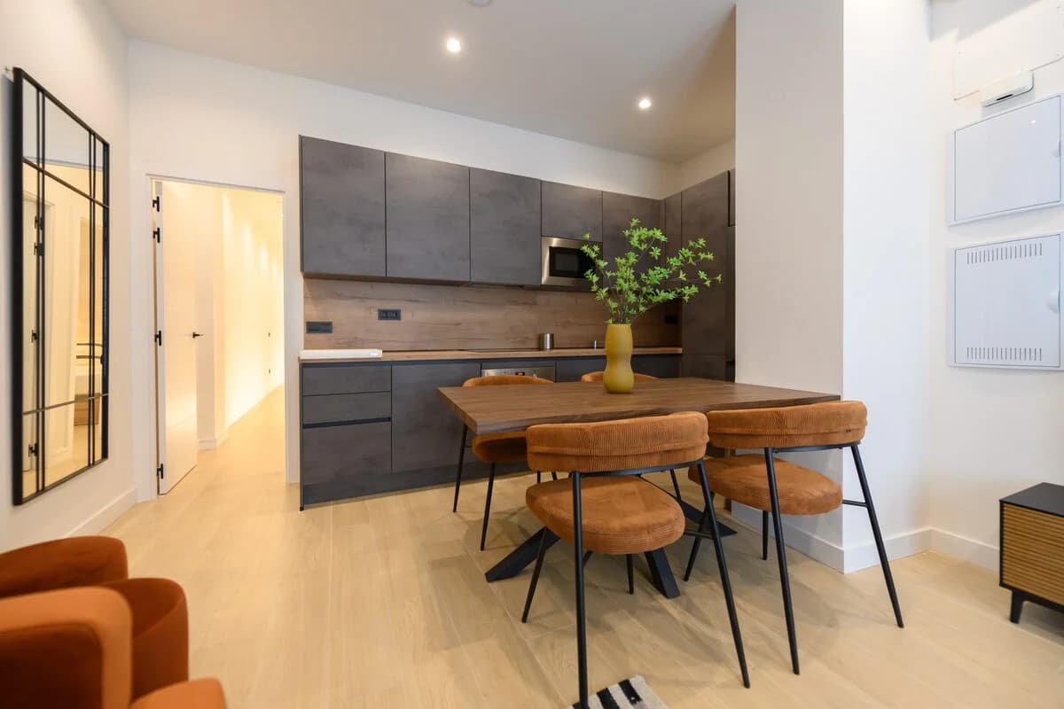 Concrete-finish kitchen with walnut dining table and corduroy chairs