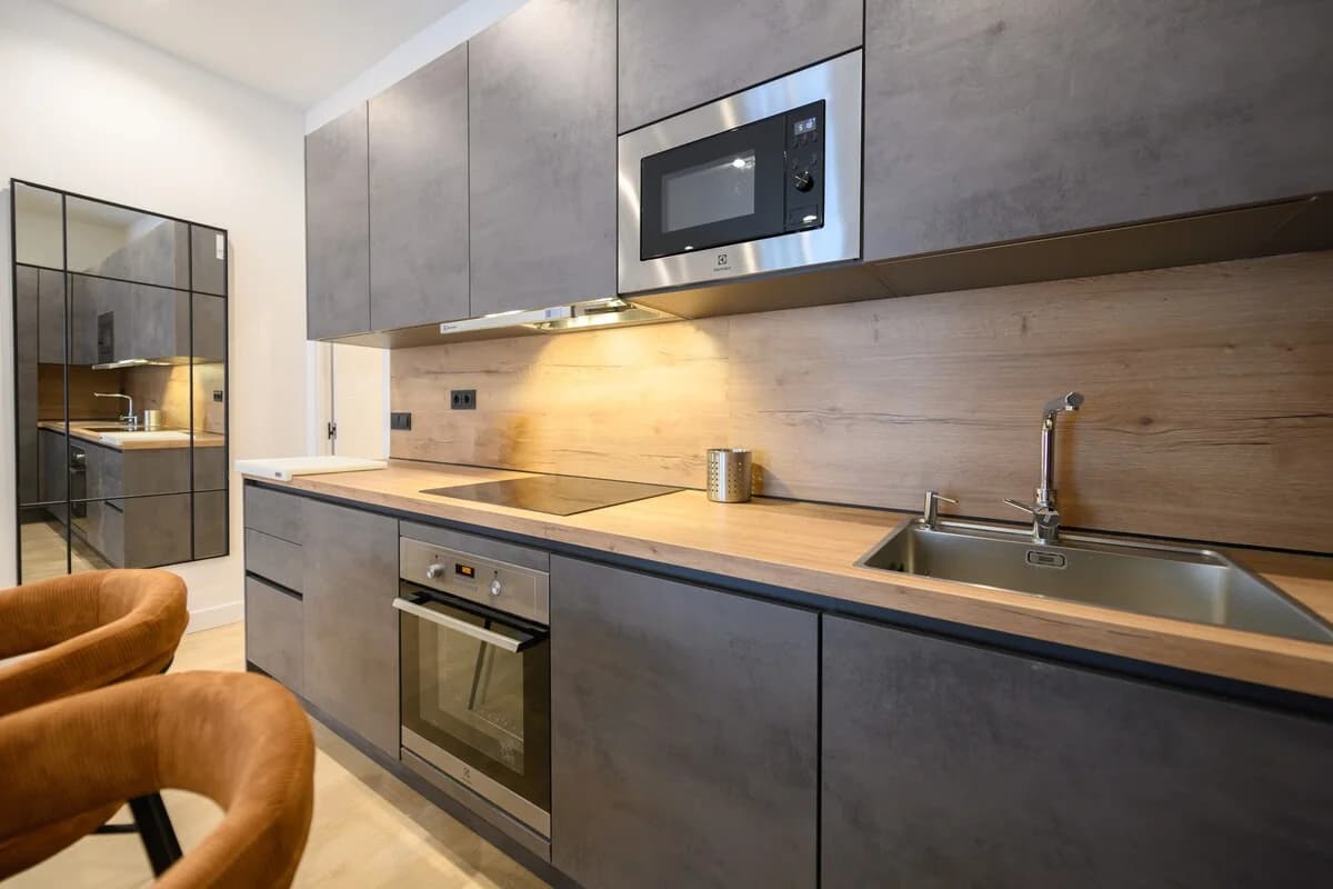 Galley kitchen detail with charcoal cabinets and warm wood backsplash