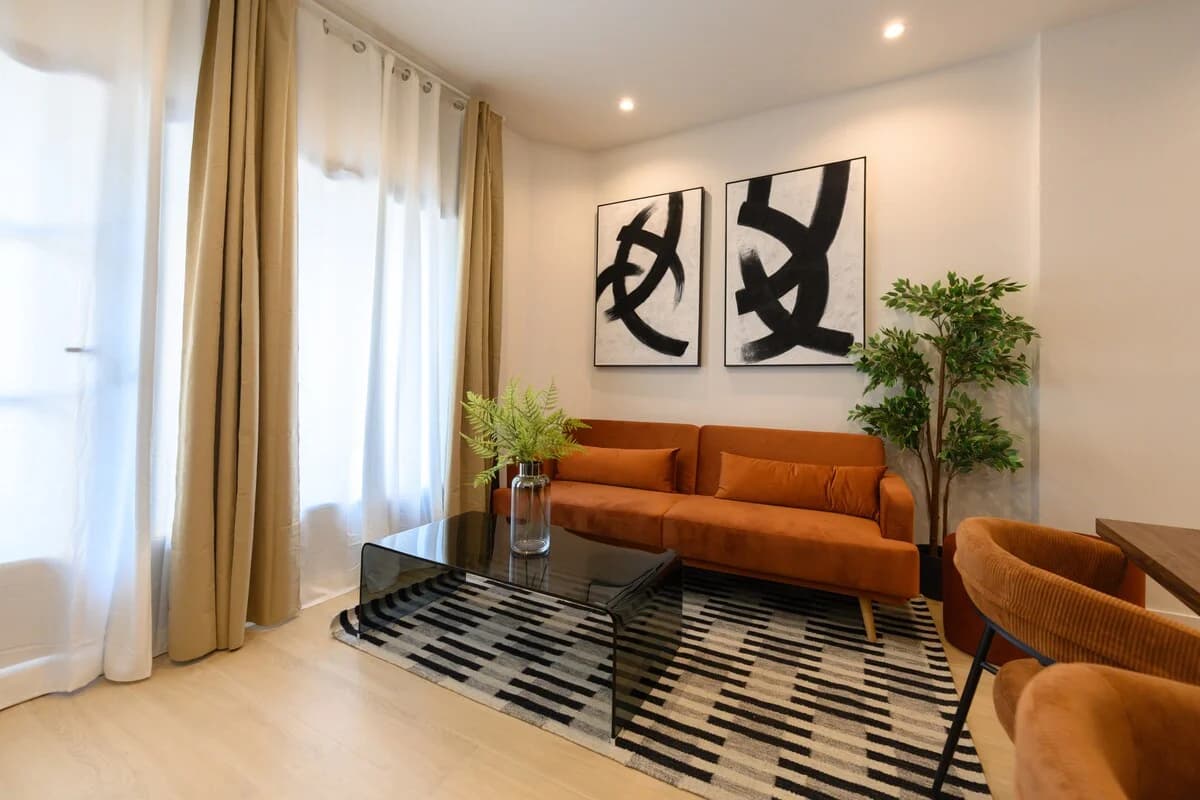 Rust velvet sofa beneath oversized abstract diptych and tall curtains