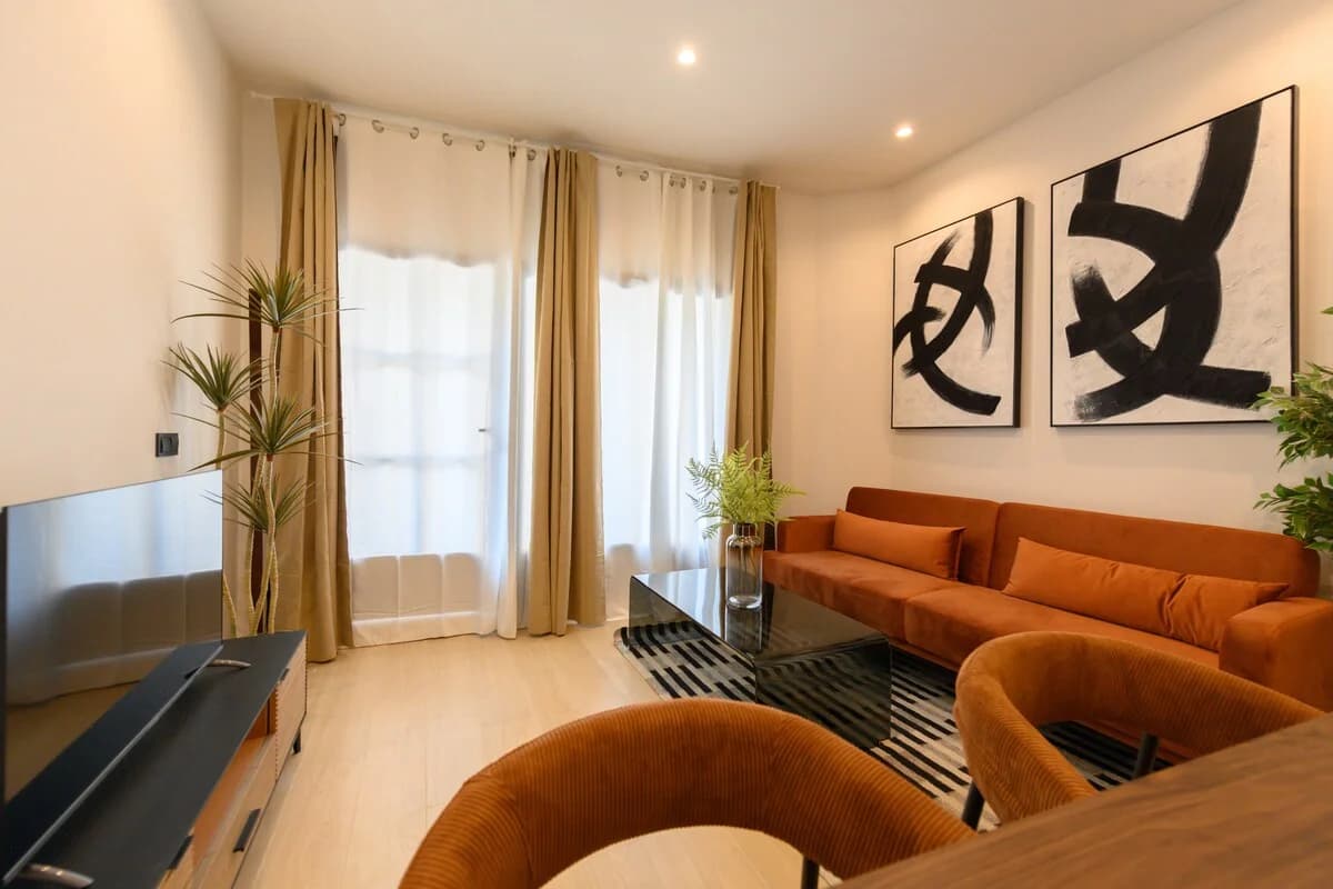 Living area with rust seating, dracaena plant and abstract gallery