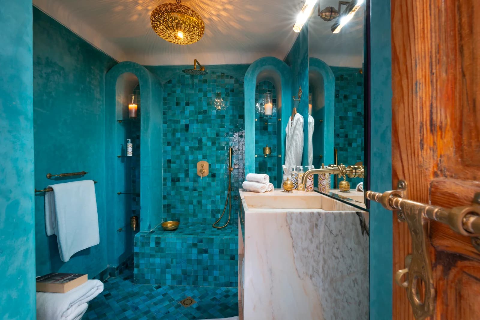 Turquoise zellige bathroom with arched shower niches and brass fittings