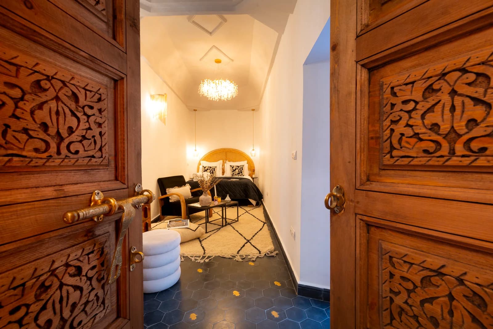 Carved double doors framing romantic bedroom with chandelier
