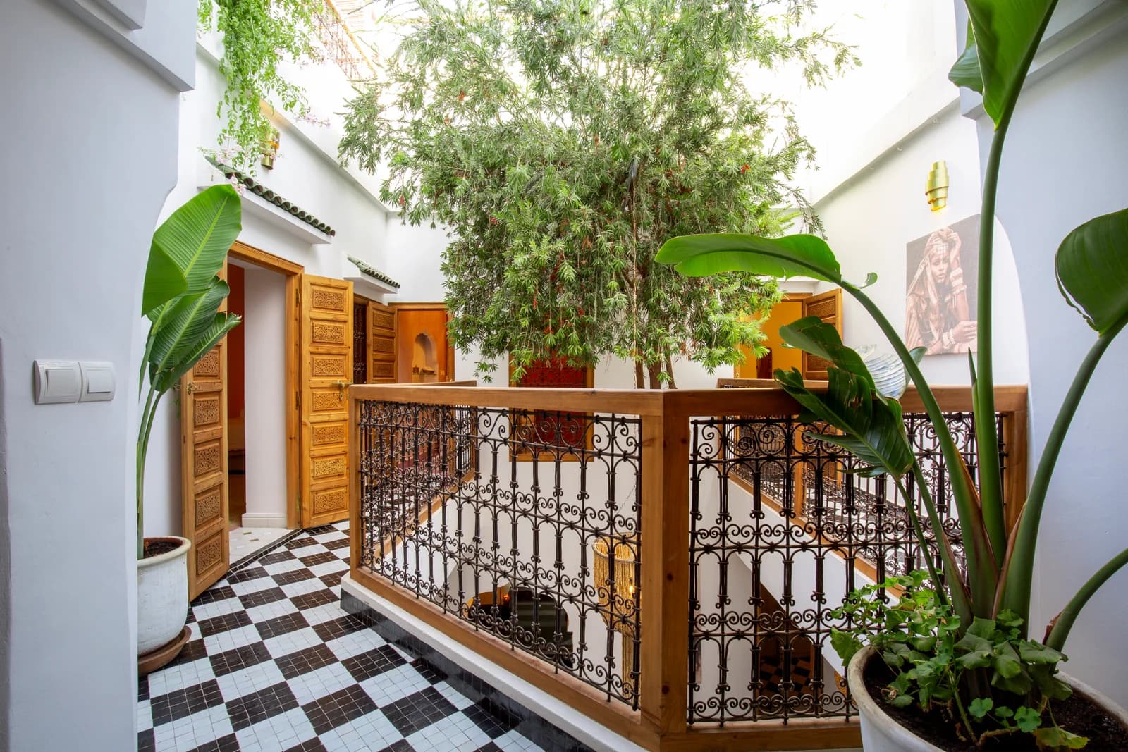 Riad inner courtyard balcony with checkered tile and tree canopy