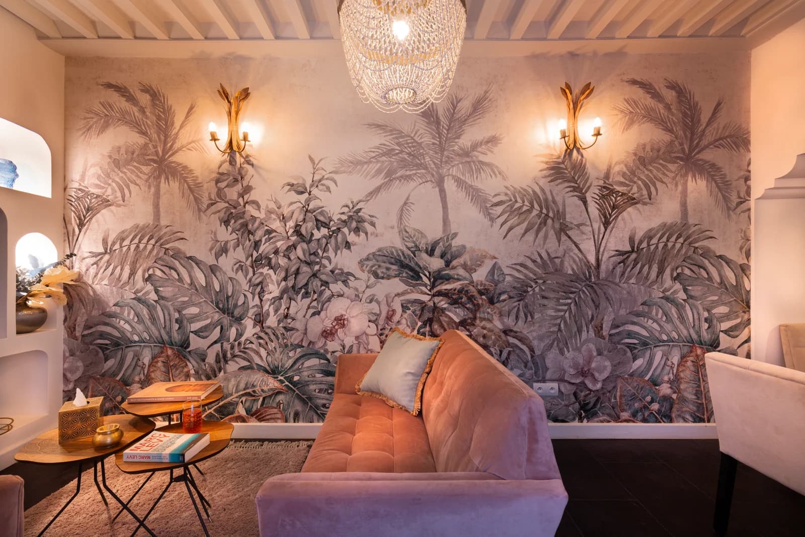 Velvet sofa against tropical mural with crystal chandelier above