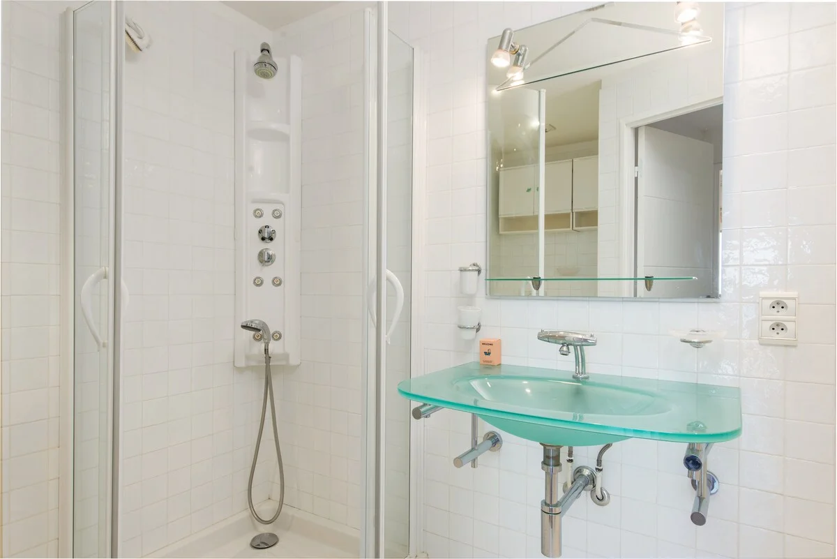 Bathroom with glass-tray sink, white tiles and walk-in shower
