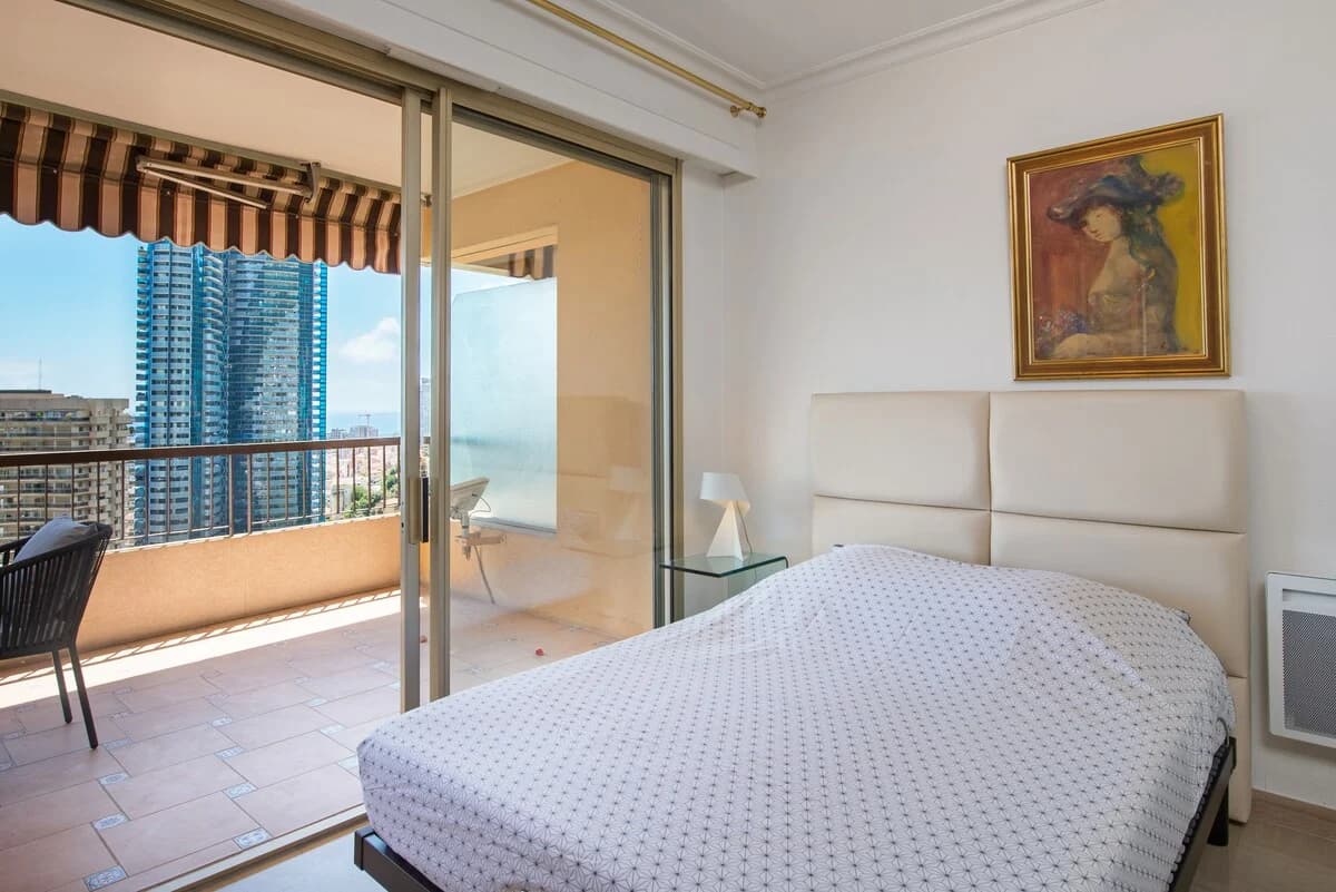 Bedroom with sliding doors to private terrace and city-tower view