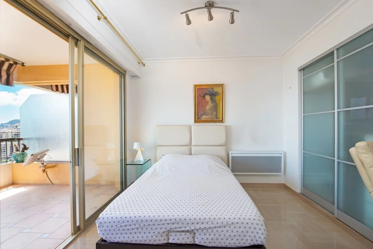 Sun-filled bedroom with glass terrace doors and vintage portrait