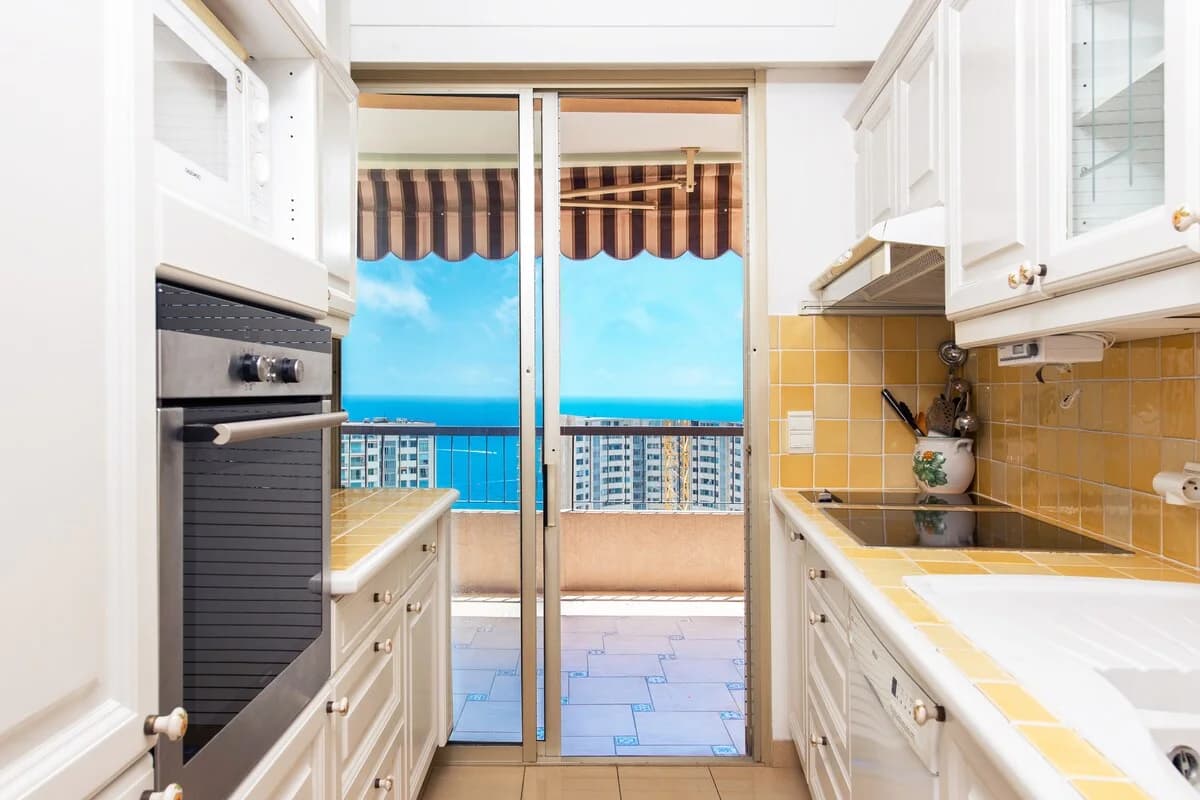 Galley kitchen with yellow-tile counter opening to sea-view terrace