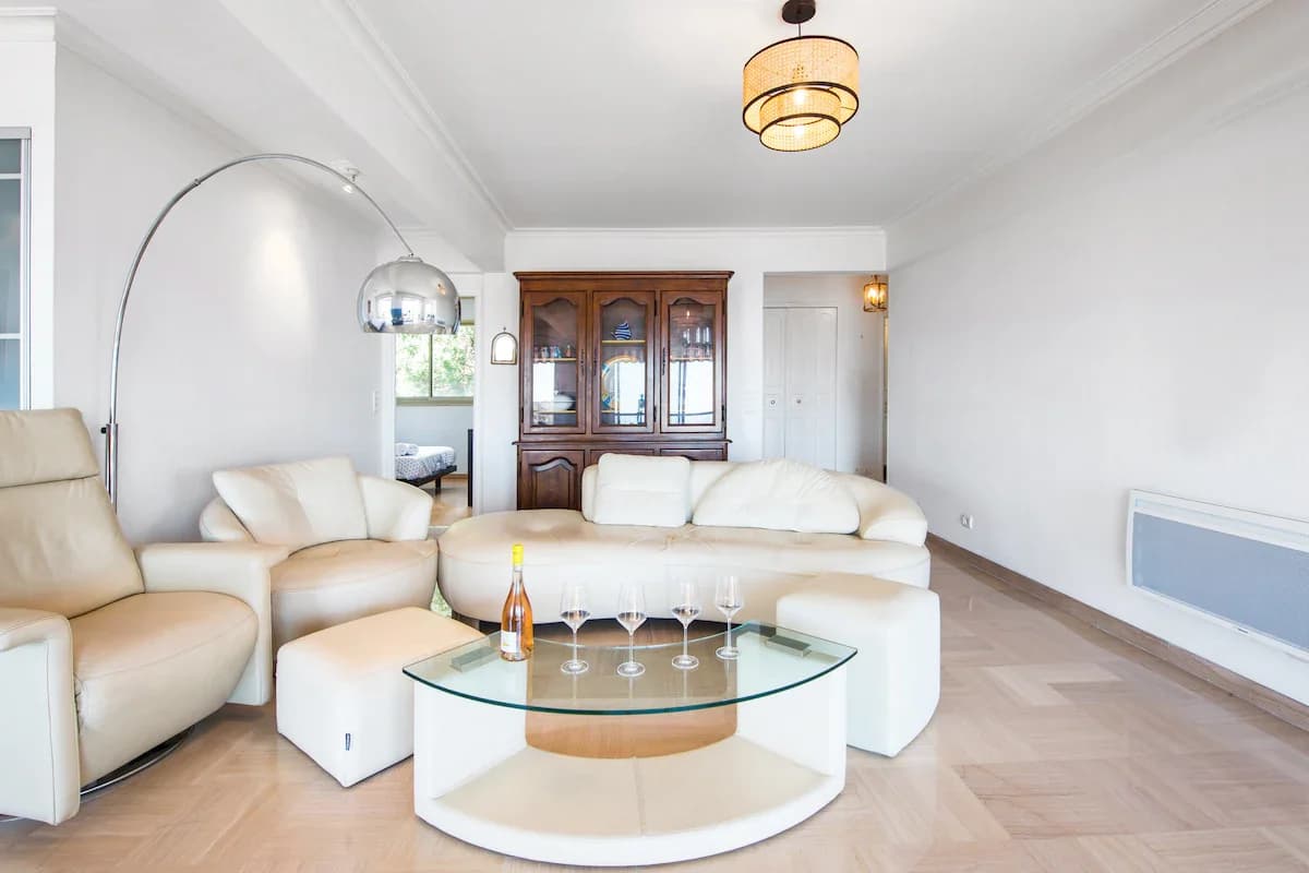 Living room with cream sofa, glass coffee table, parquet floor and arched lamp