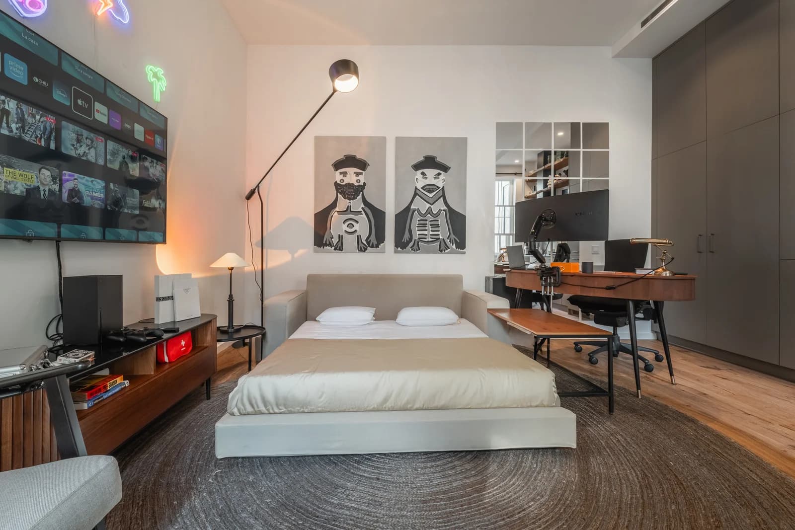 Studio-style bedroom with dual monitor desk and graffiti diptych