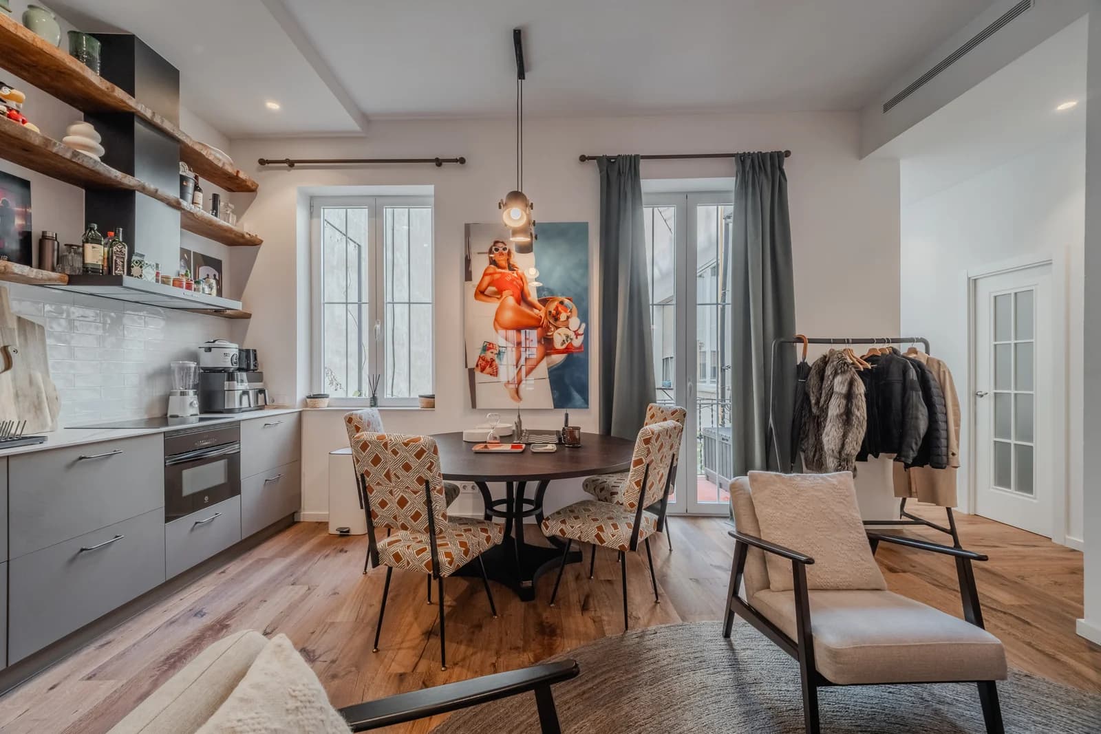 Round dining table beside galley kitchen with patterned chairs