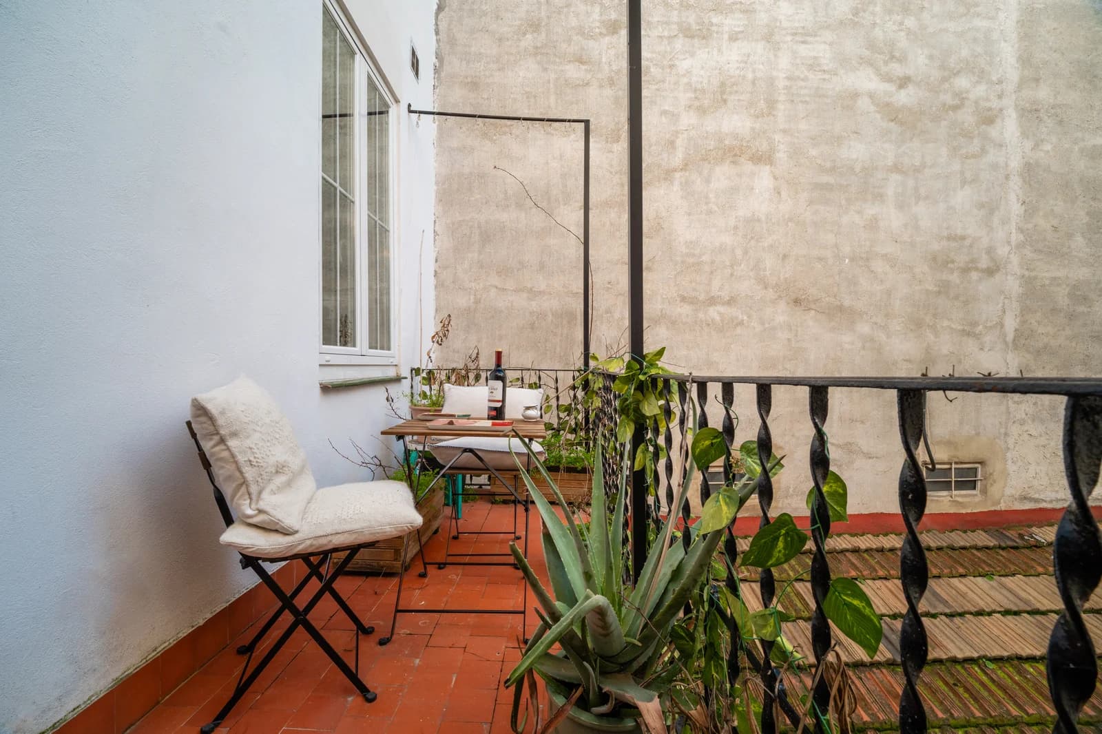 Tucked terracotta-tile balcony with bistro chair and aloe planting