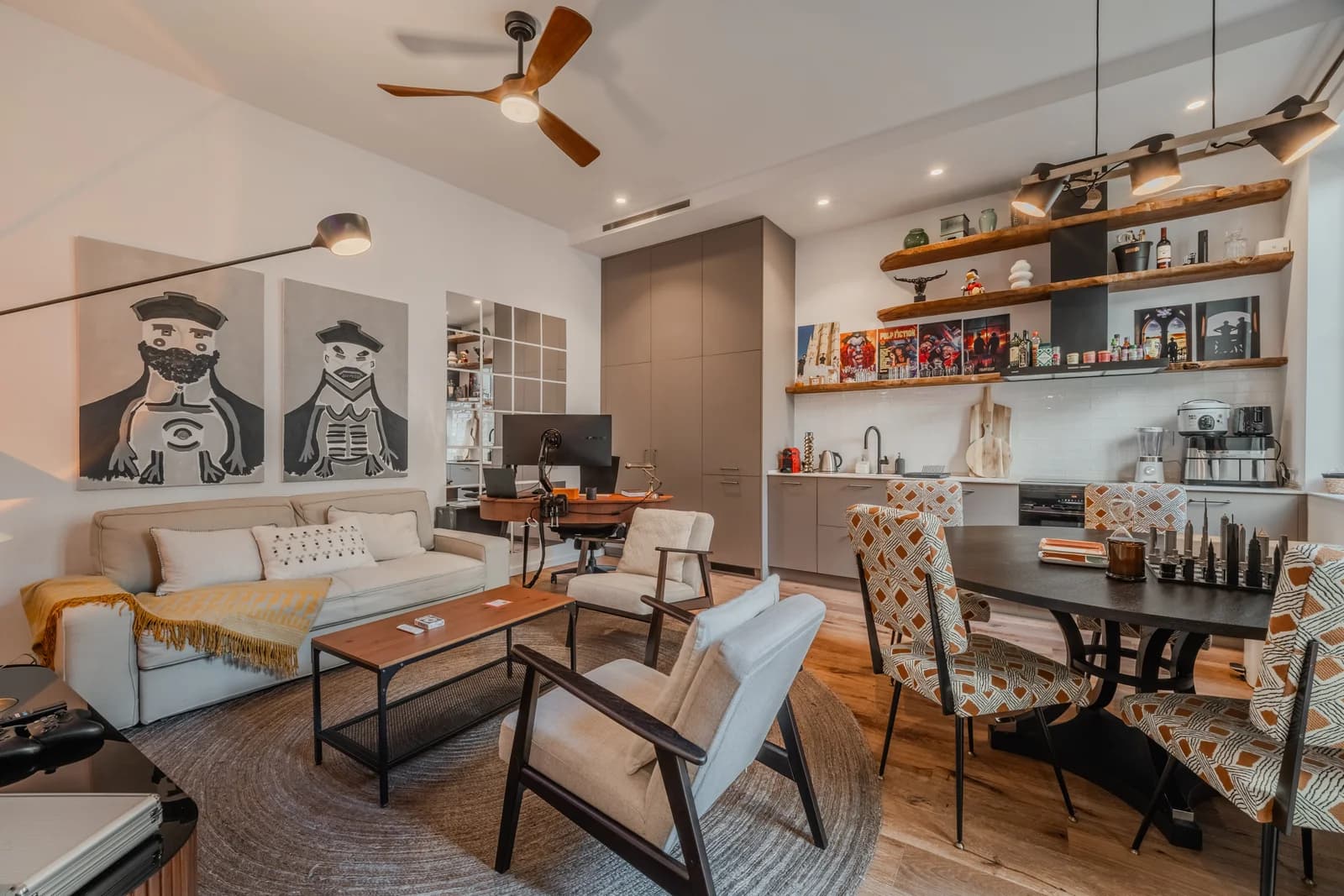 Open lounge-kitchen with portrait diptych, rattan bar and wood floors