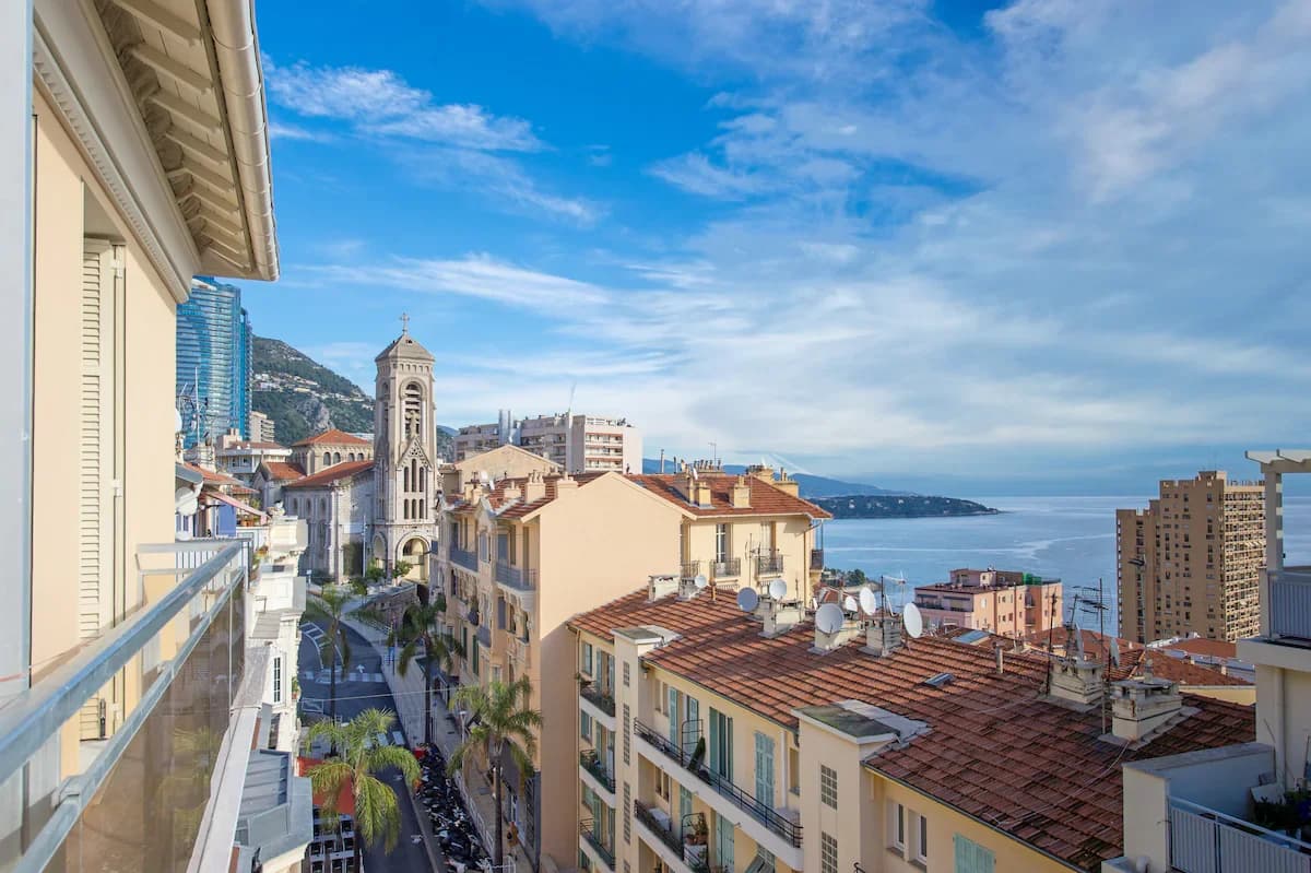 Balcony view across Monaco bell tower toward sparkling Mediterranean