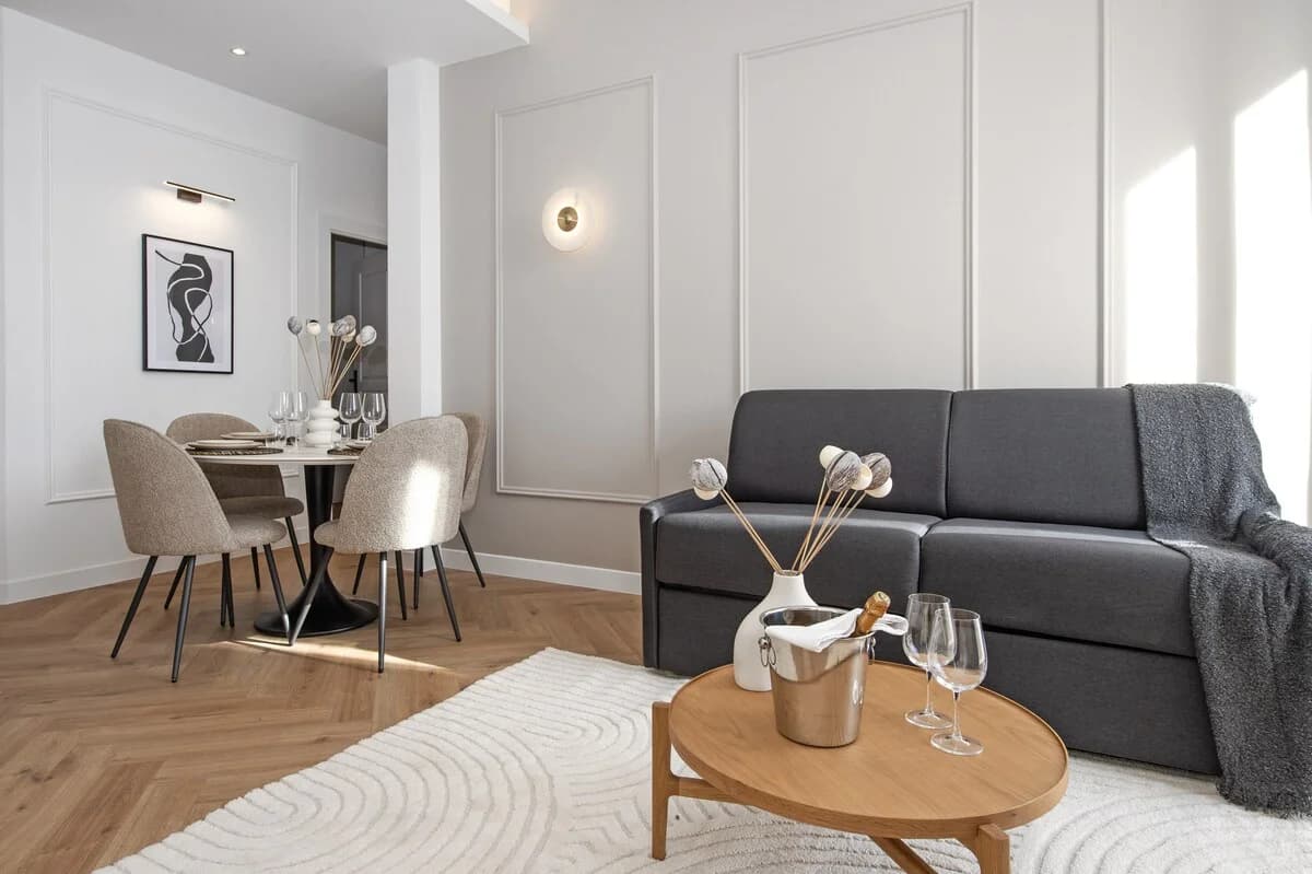 Charcoal sofa and bouclé dining chairs beside panel-moulded wall