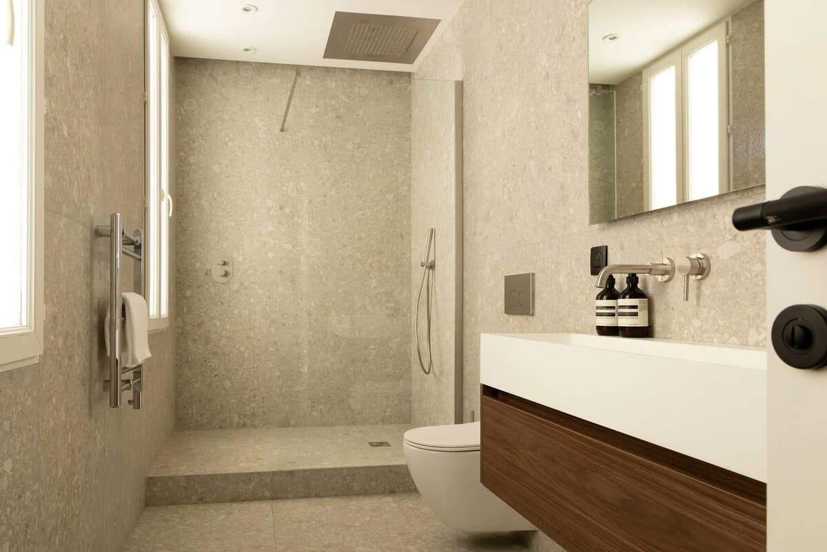 Stone-clad shower room with walnut floating vanity and brushed fittings