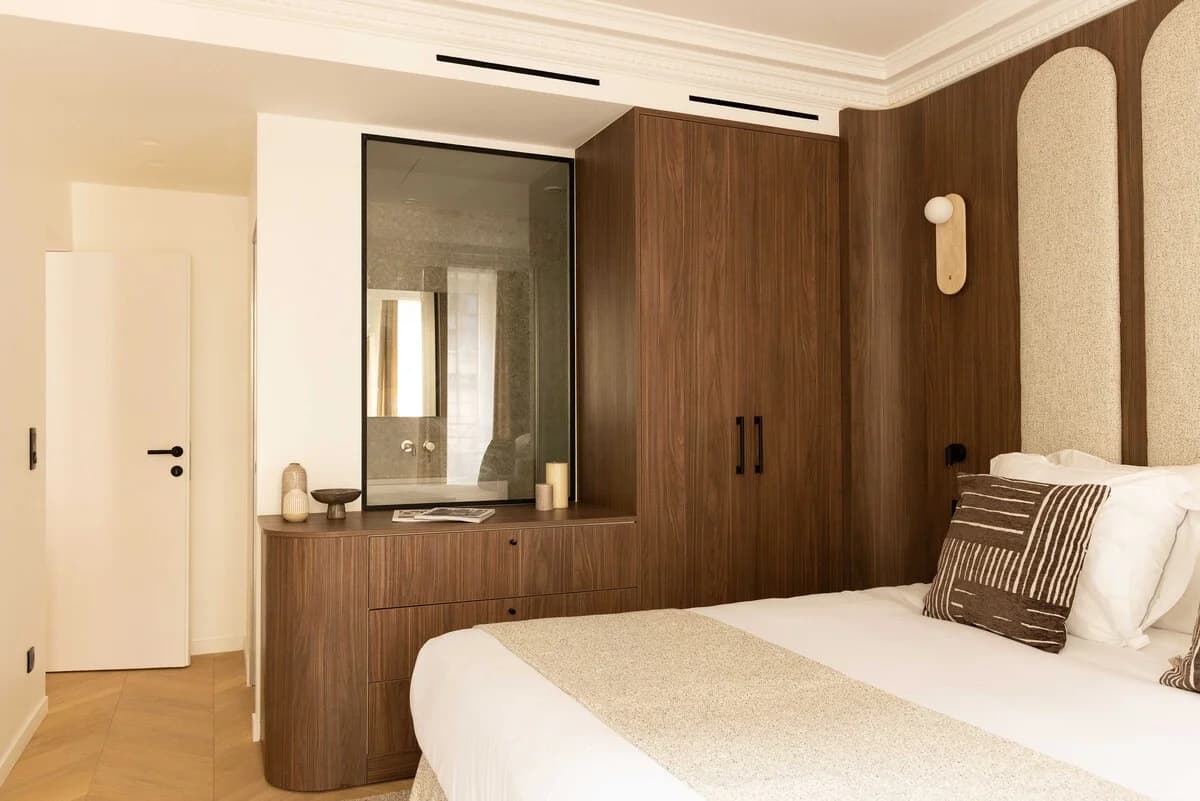 Walnut-clad bedroom with internal window into ensuite bathroom