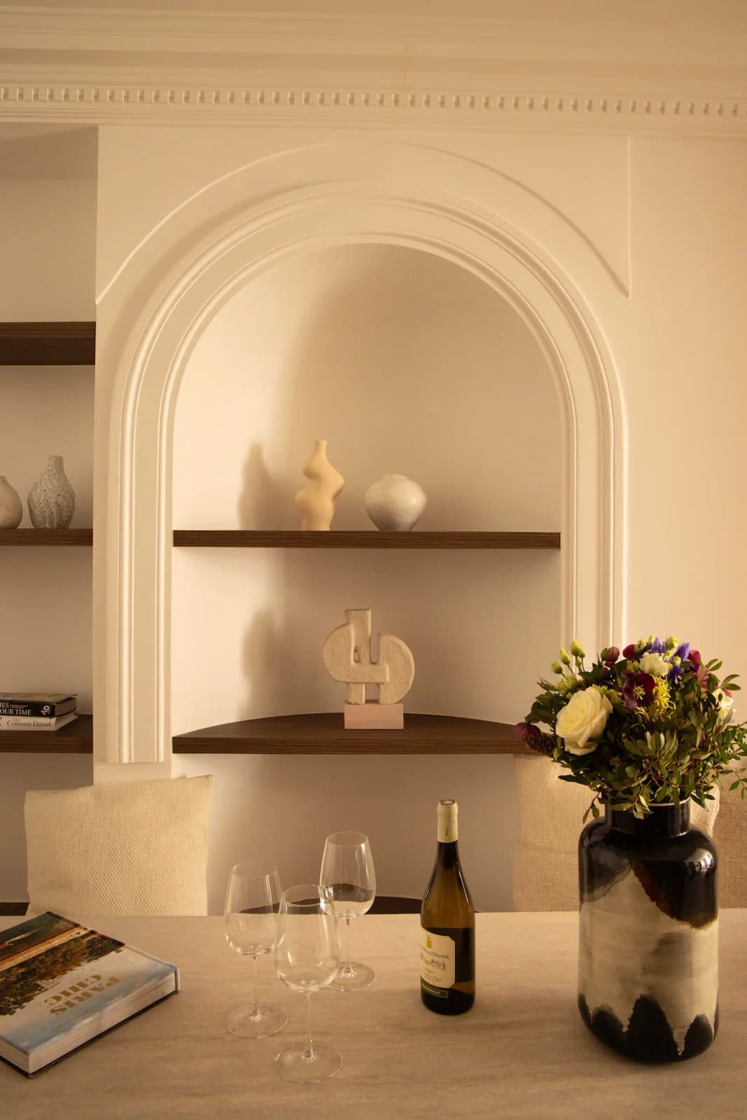 Plaster archway niche with sculptural ceramics and dining still life