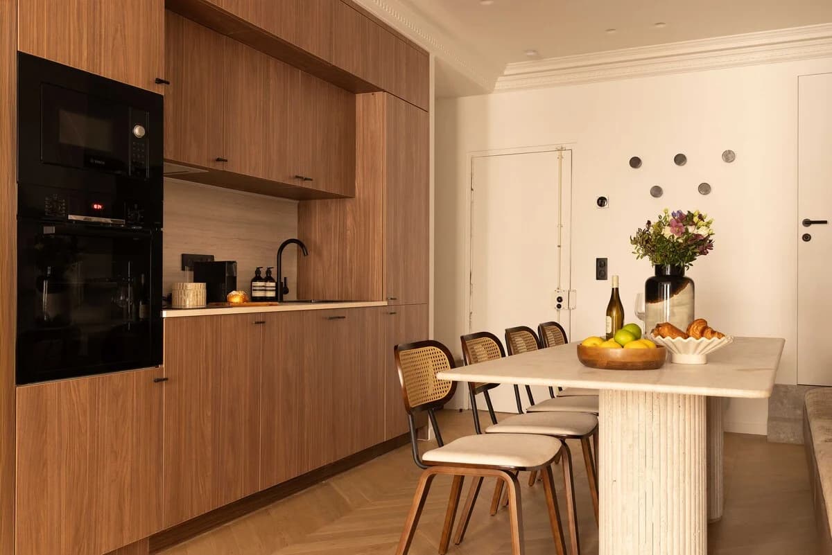 Walnut kitchen with travertine fluted dining table and cane chairs