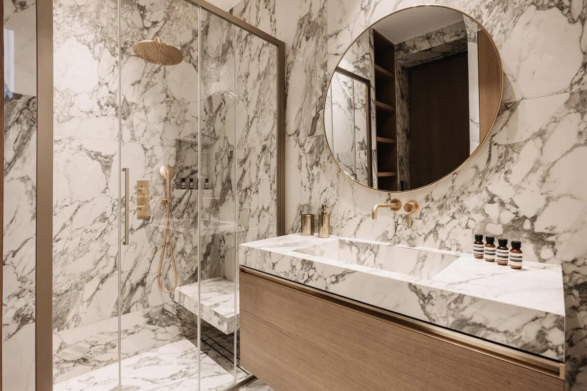 Calacatta marble bathroom with brass fittings and round mirror