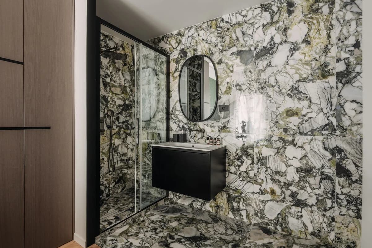 Bold green-veined marble bathroom with black vanity and walk-in shower