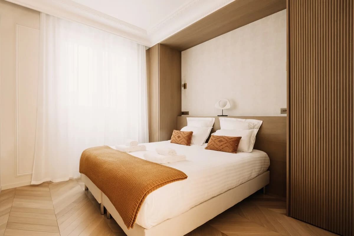 Bedroom with rust accents, fluted wood panels and sheer curtains