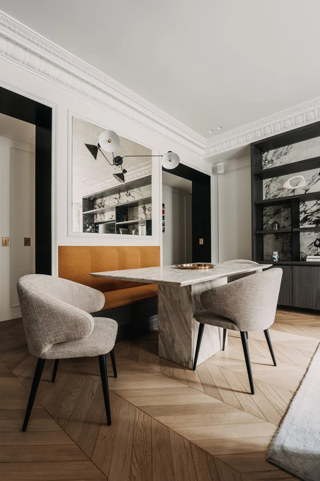 Marble dining table with mustard banquette and twin sconces