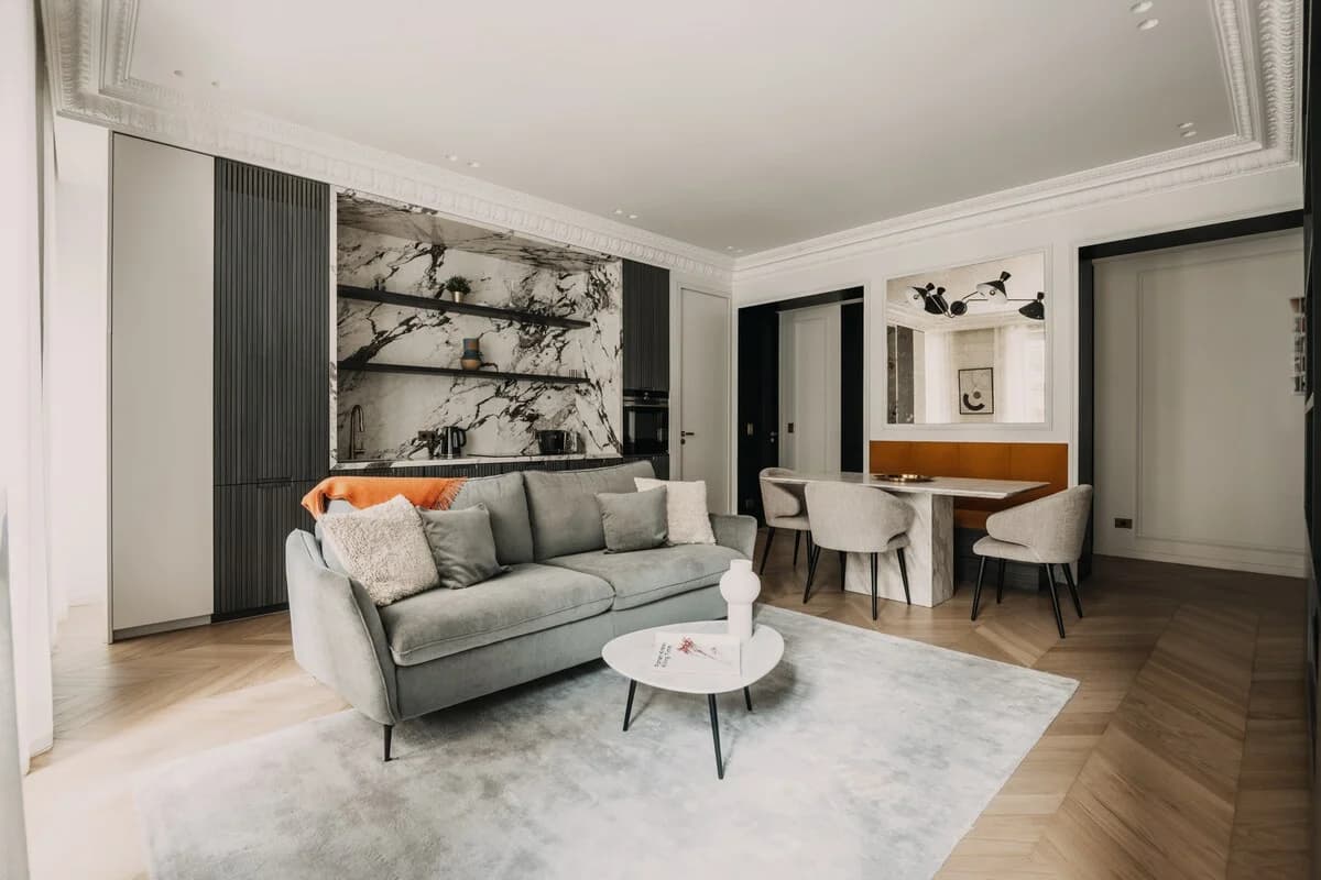 Wide Haussmann living room with grey sofa, marble kitchen and dining banquette