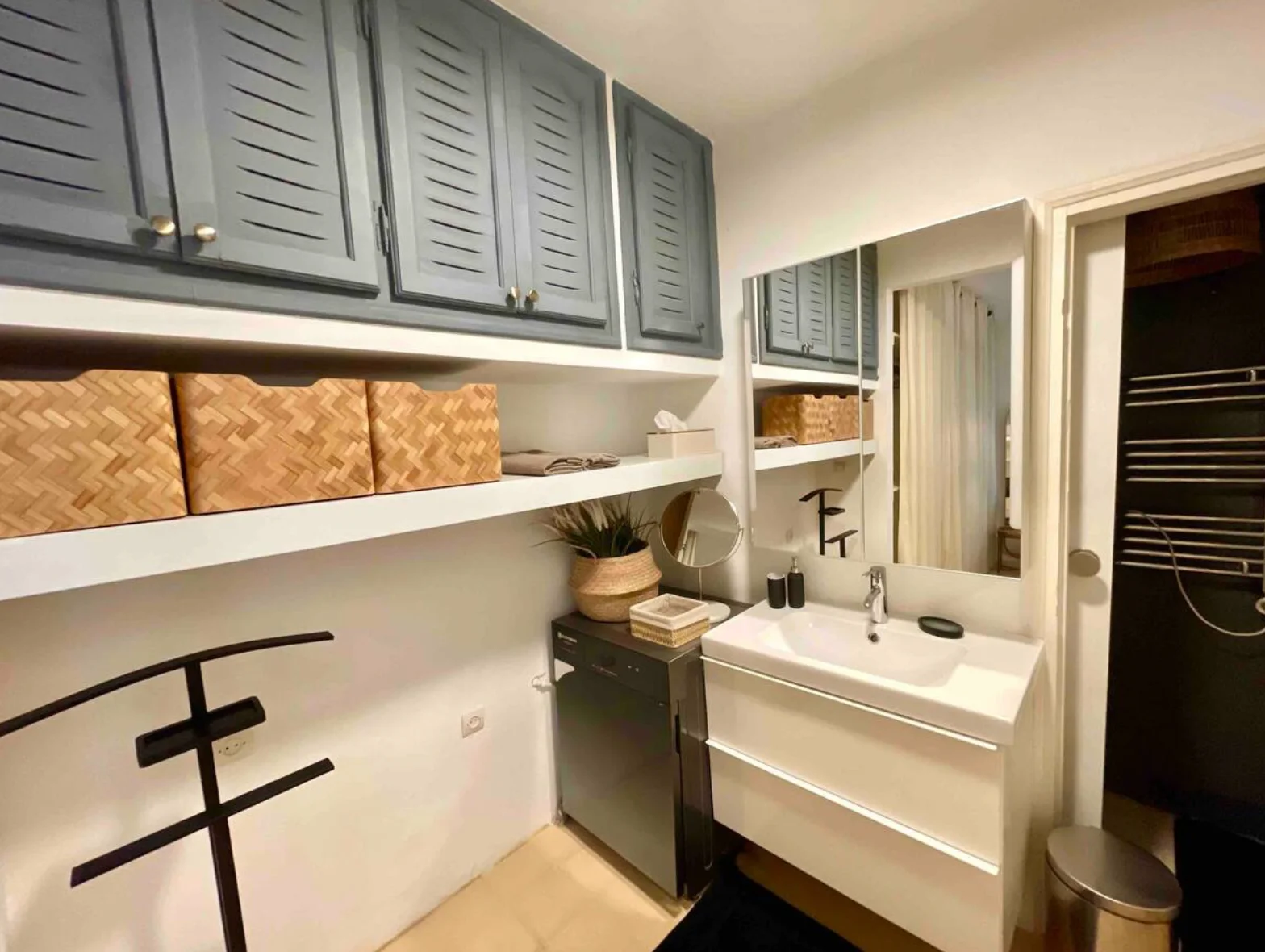 Bathroom with grey-blue louvred cabinets and woven storage baskets