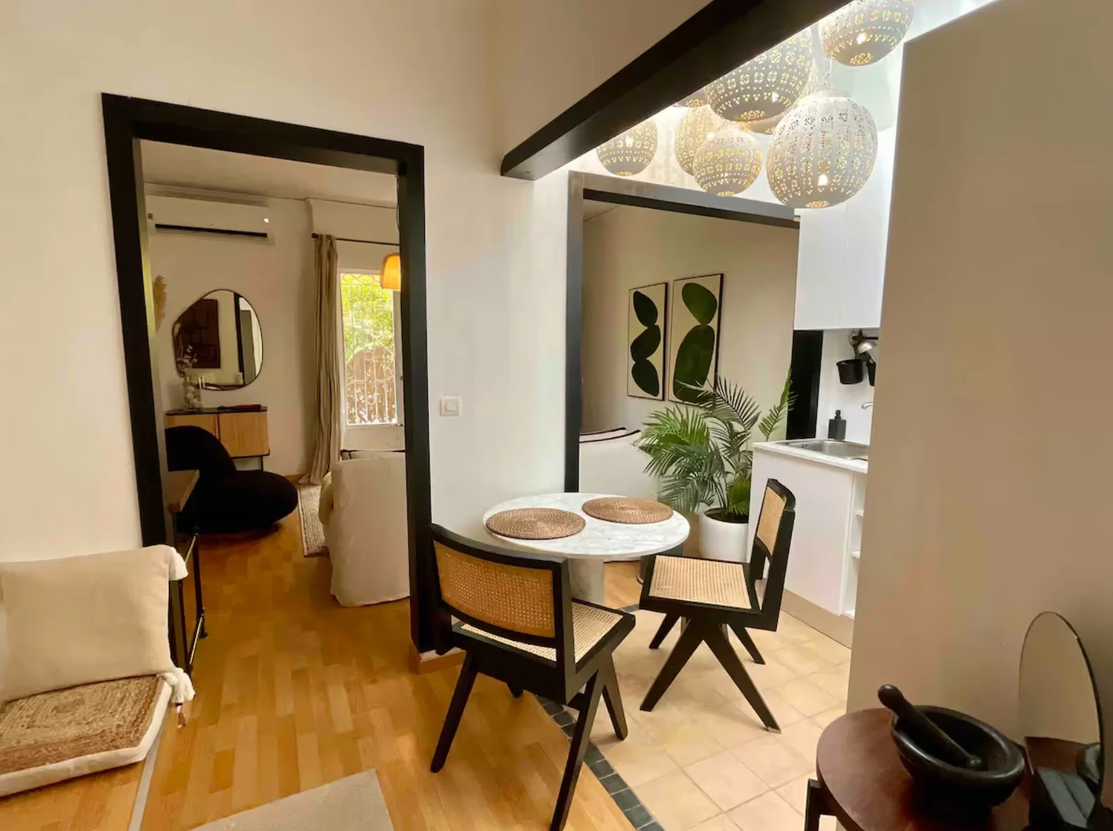 Bistro dining table with cane chairs beneath cluster of woven pendants