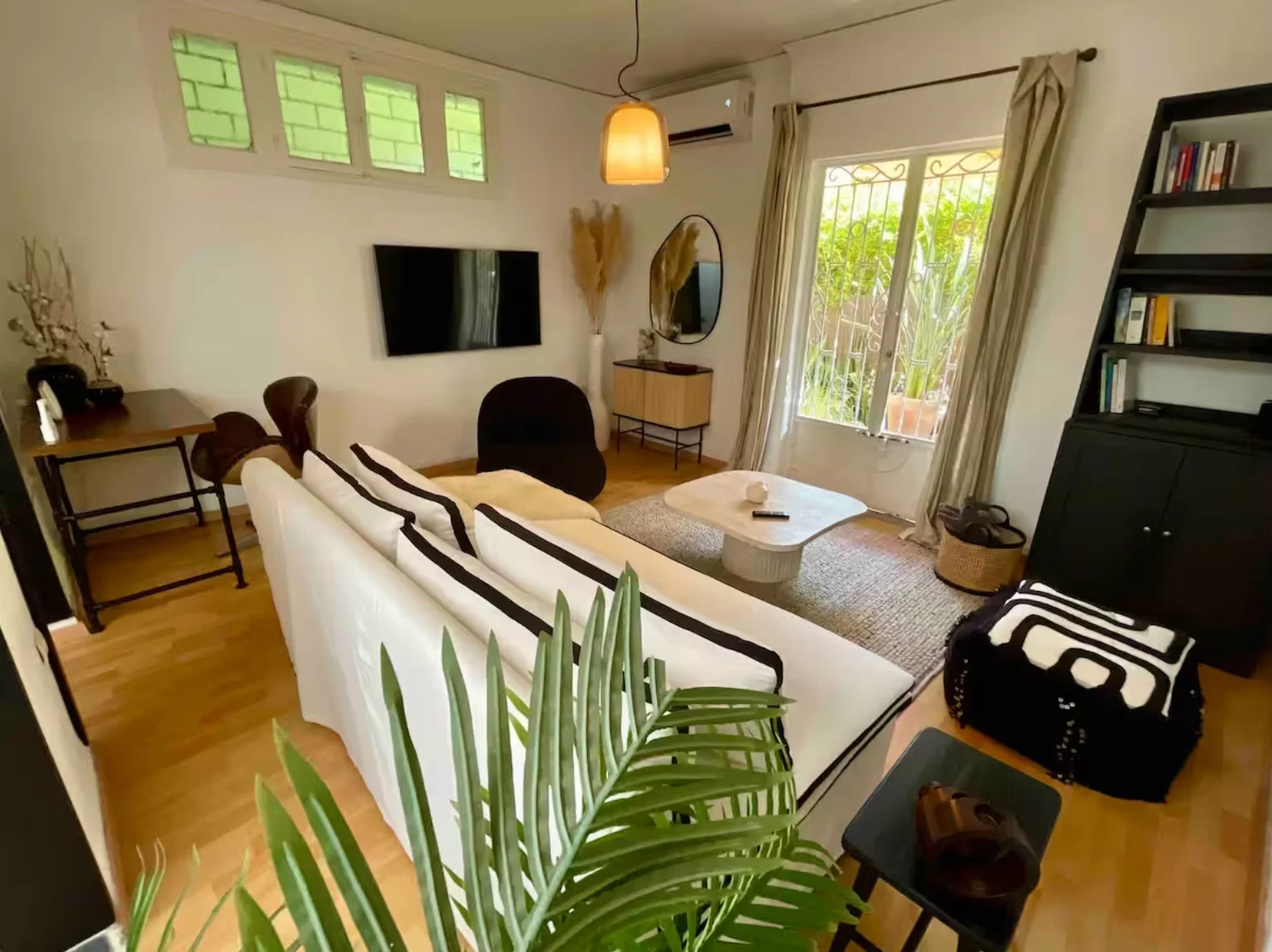 Living area with garden view, monochrome accents and ratan pendant