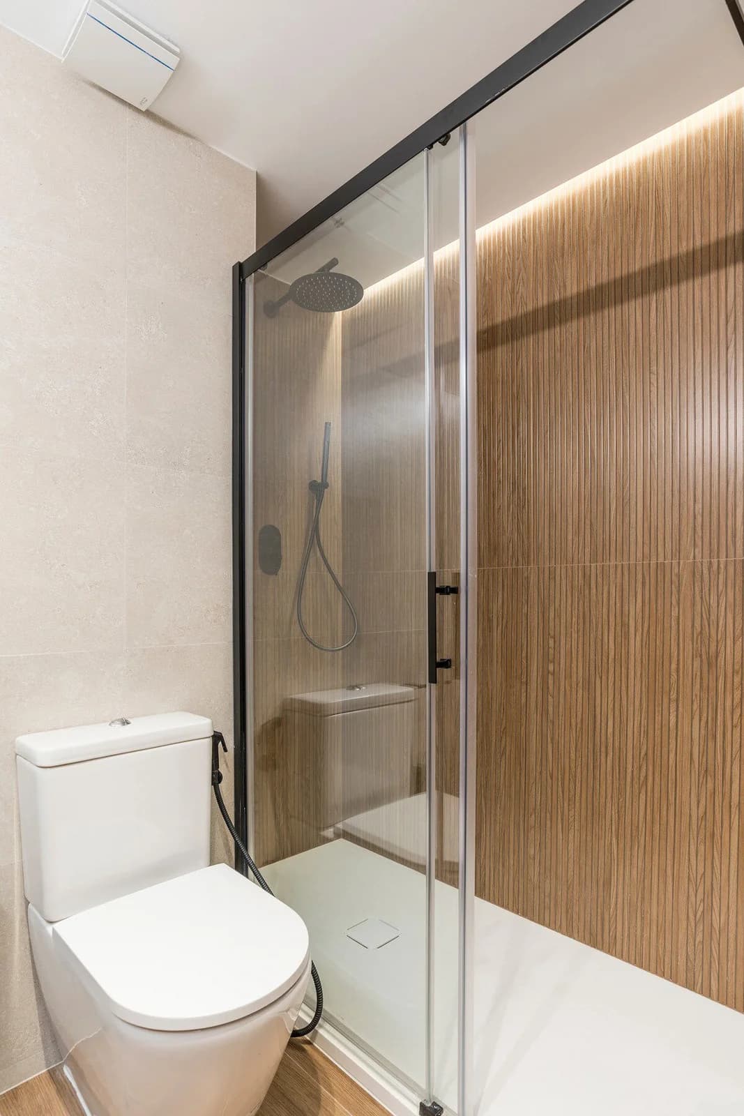 Walk-in shower clad in slatted oak with backlit warmth