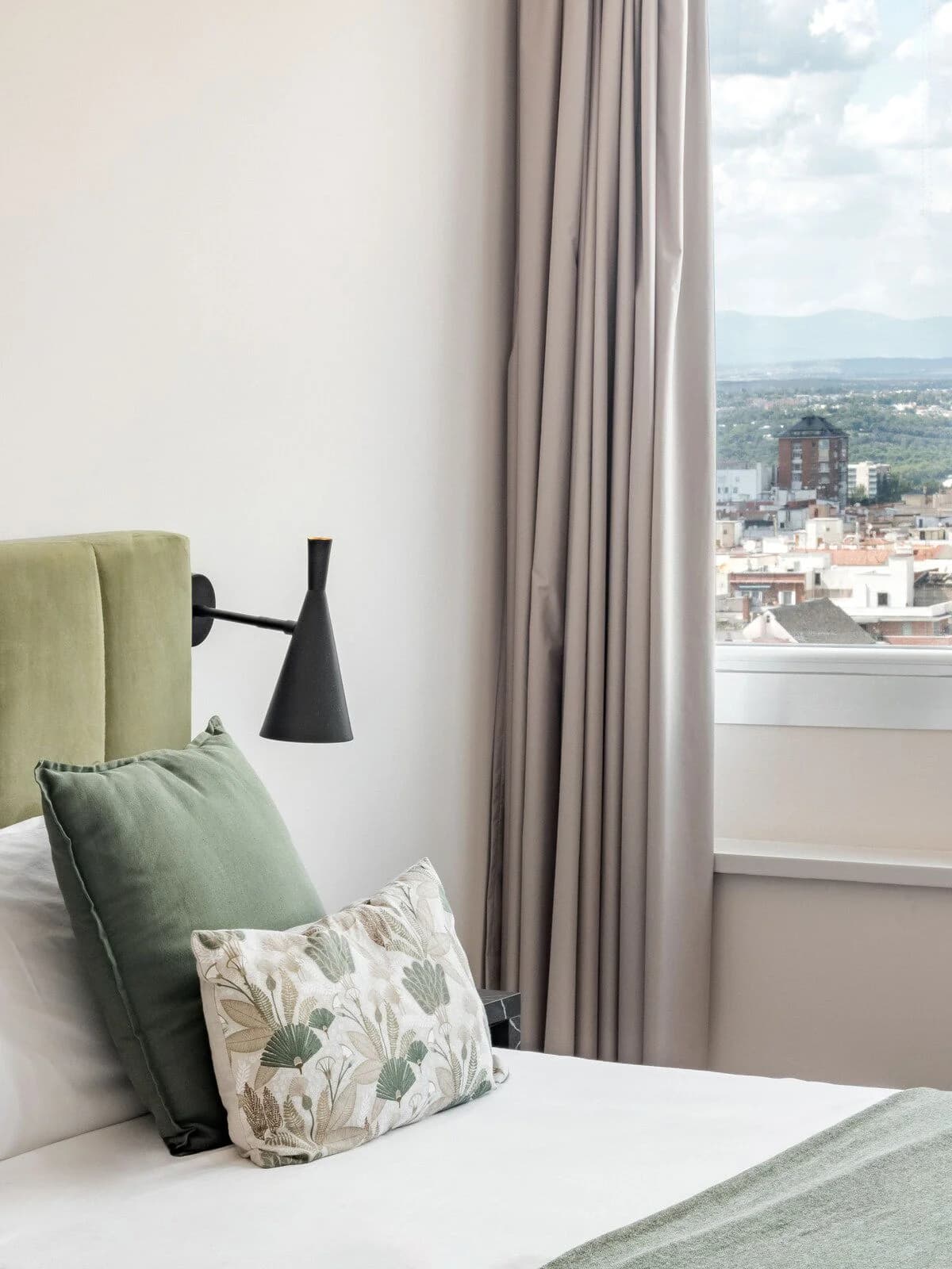 Bedside detail with mountain view through floor-length curtains