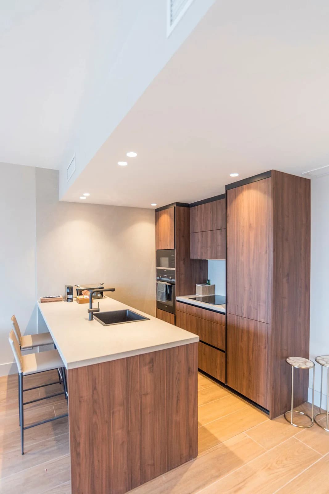 Walnut galley kitchen with warm overhead lighting and breakfast bar