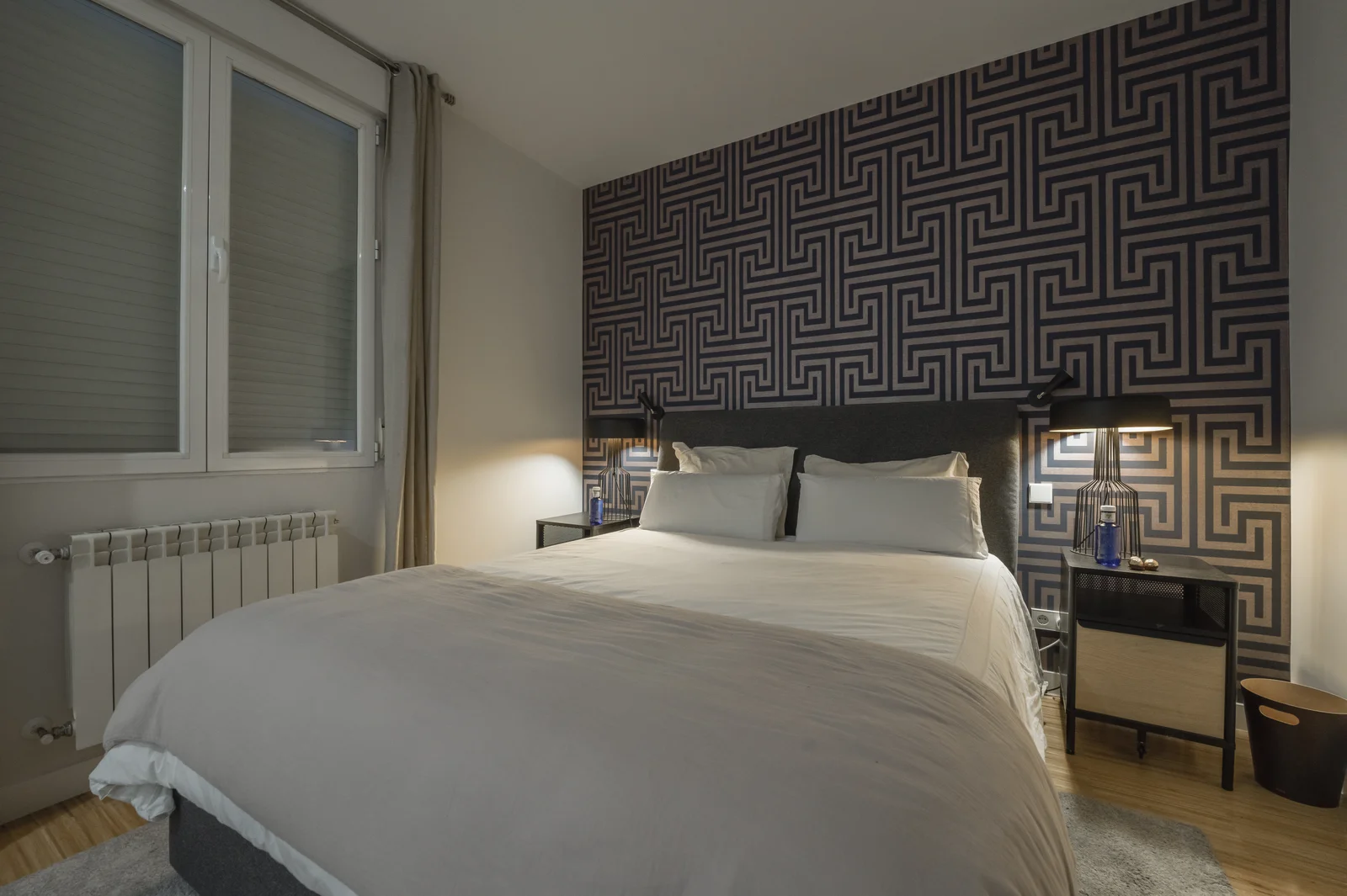 King bed against bold geometric accent wall, soft window light