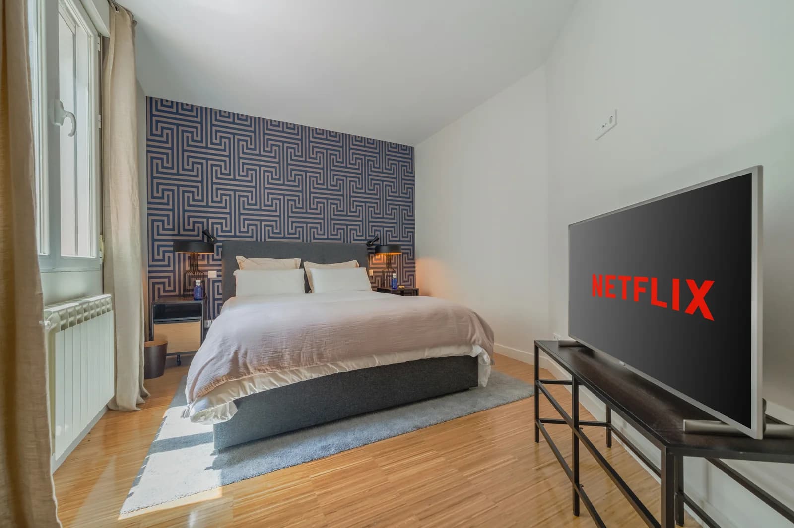 Second bedroom with patterned headboard wall and pale wood floor