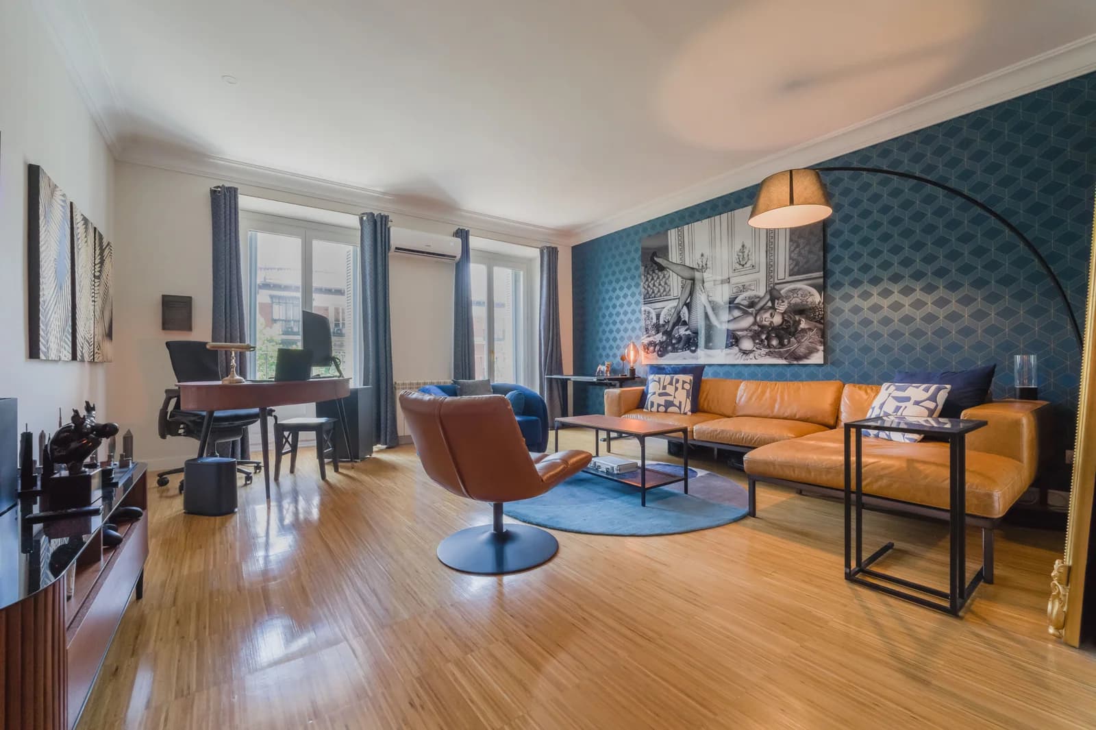 Eclectic salon with tan leather sofa, blue accents and natural light