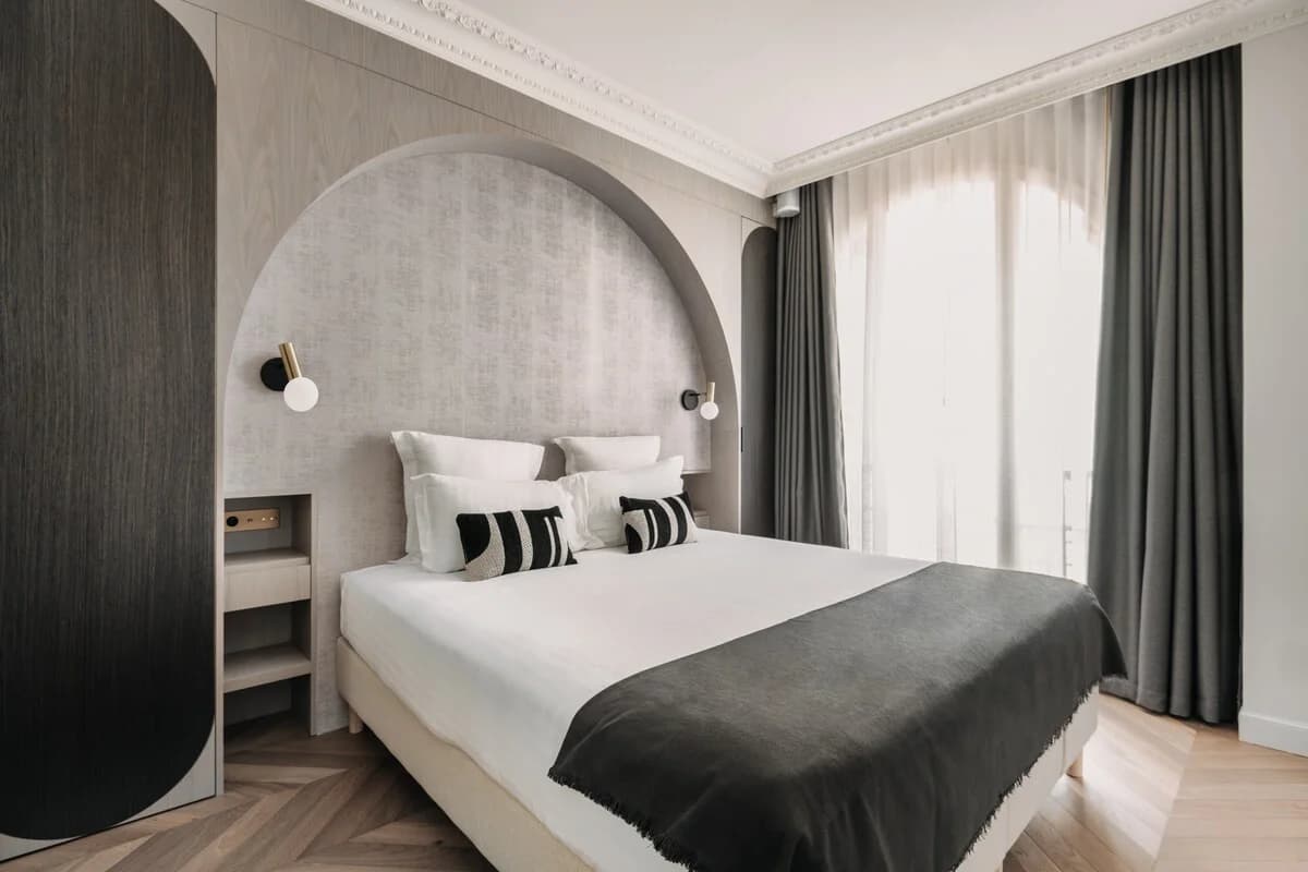 Arched headboard alcove, herringbone parquet, soft Parisian daylight
