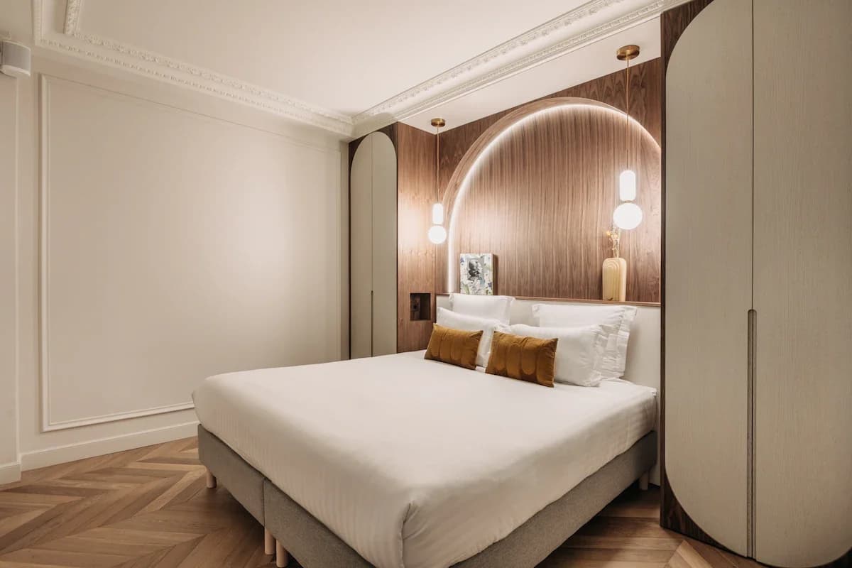 Arched walnut alcove framing the bed under ornate cornice