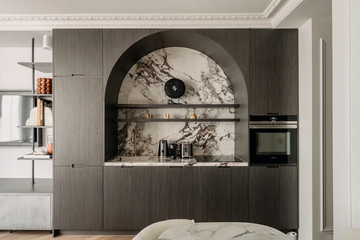 Arched calacatta marble niche framed by walnut joinery and ornate mouldings