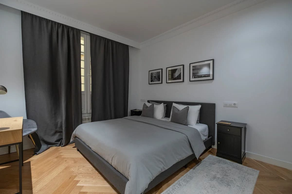 King bed with charcoal curtains, gallery prints and parquet floor