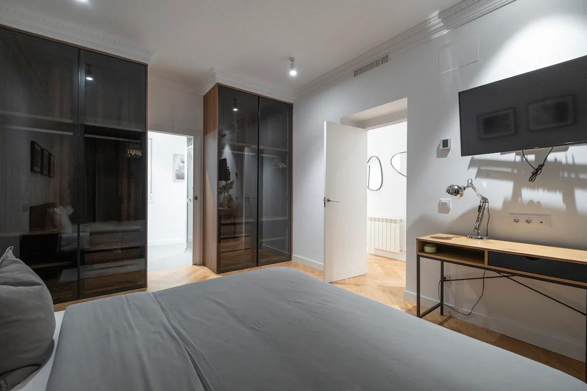 Glass wardrobes opposite bed with view through to corridor