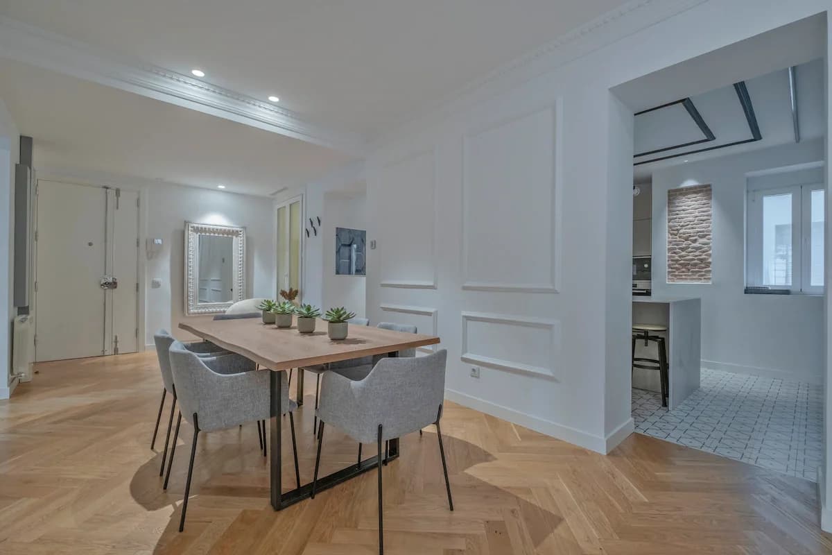 Wide dining area with grey upholstered chairs and herringbone parquet