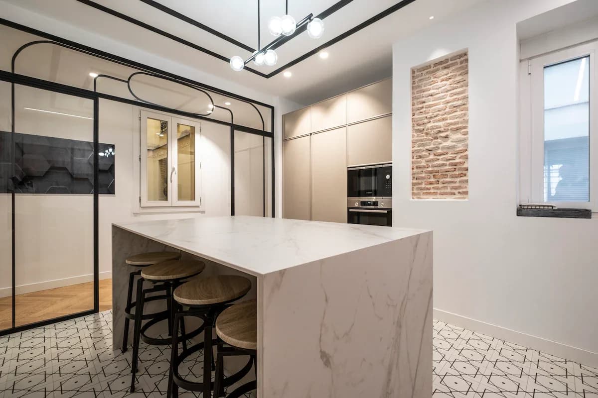 Marble waterfall island, exposed brick niche and graphic tile floor