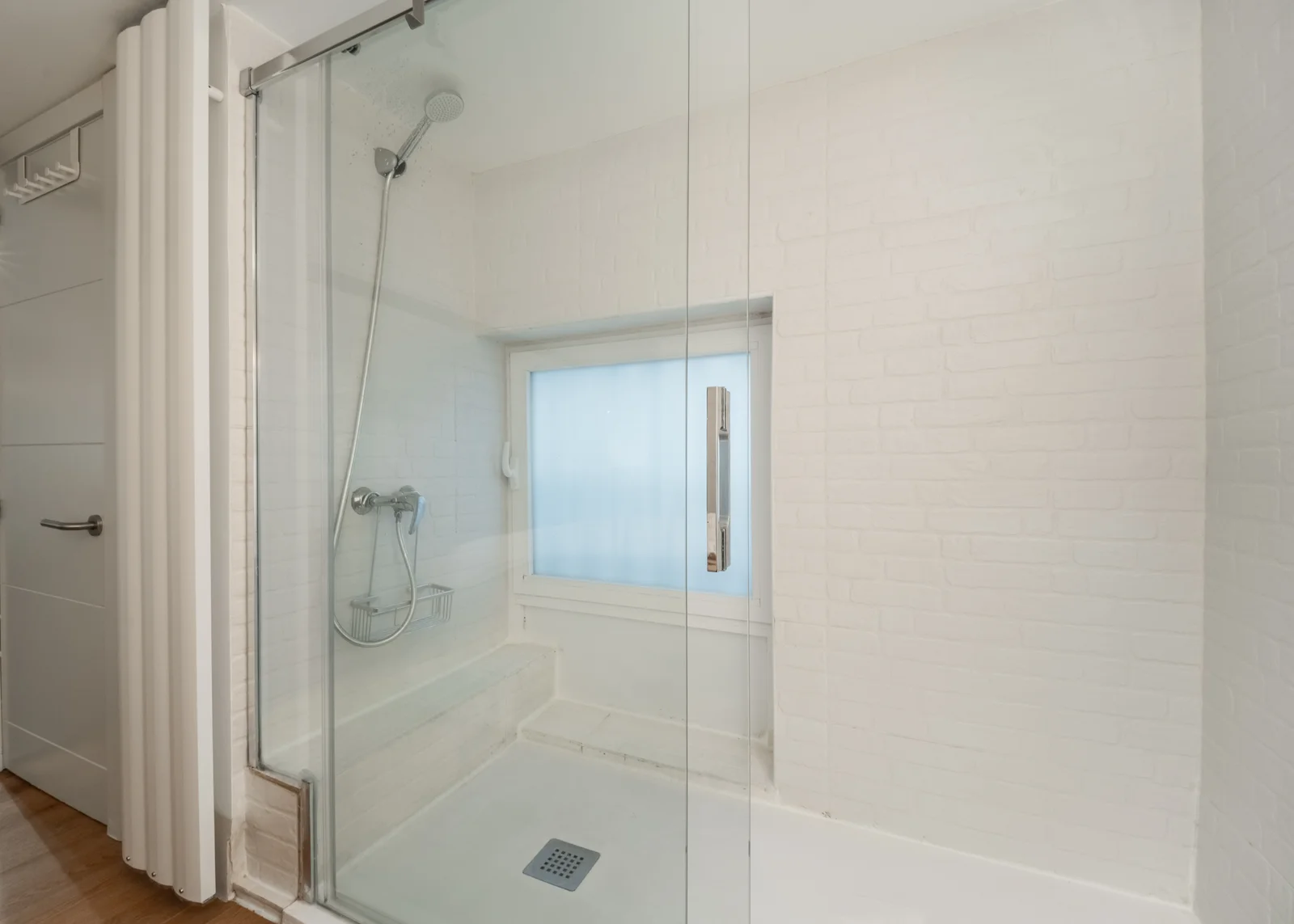 Whitewashed brick walk-in shower with frosted window light