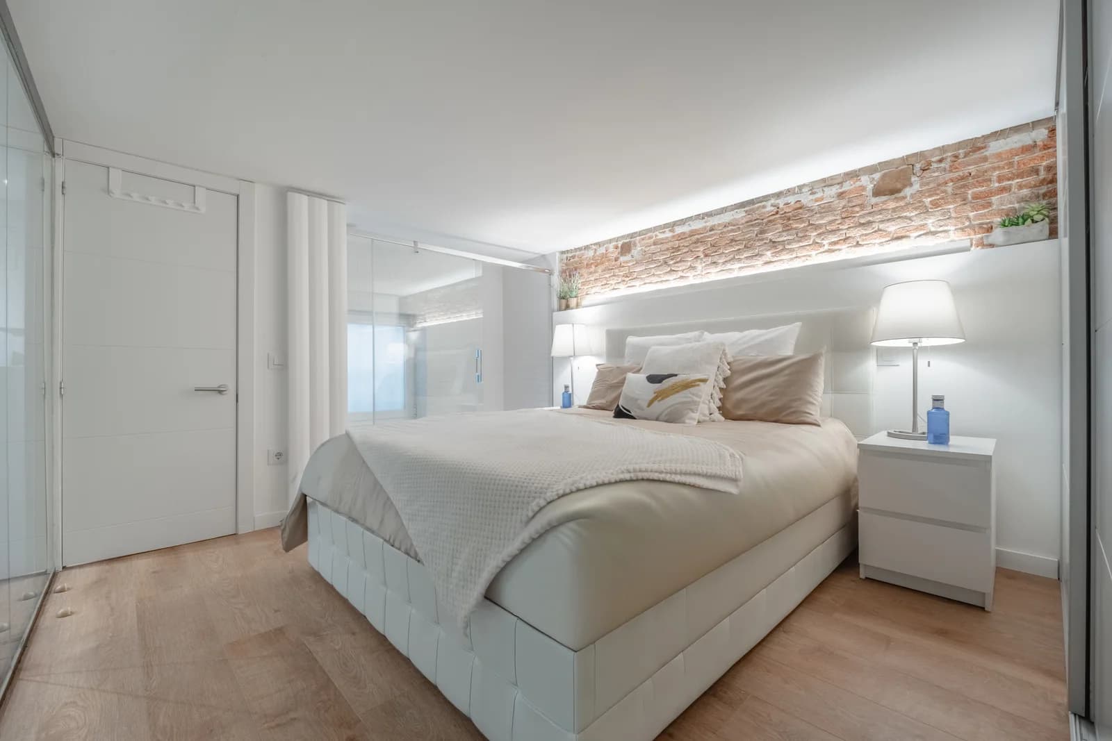 Crisp white bedroom with brick light-strip and bedside lamps