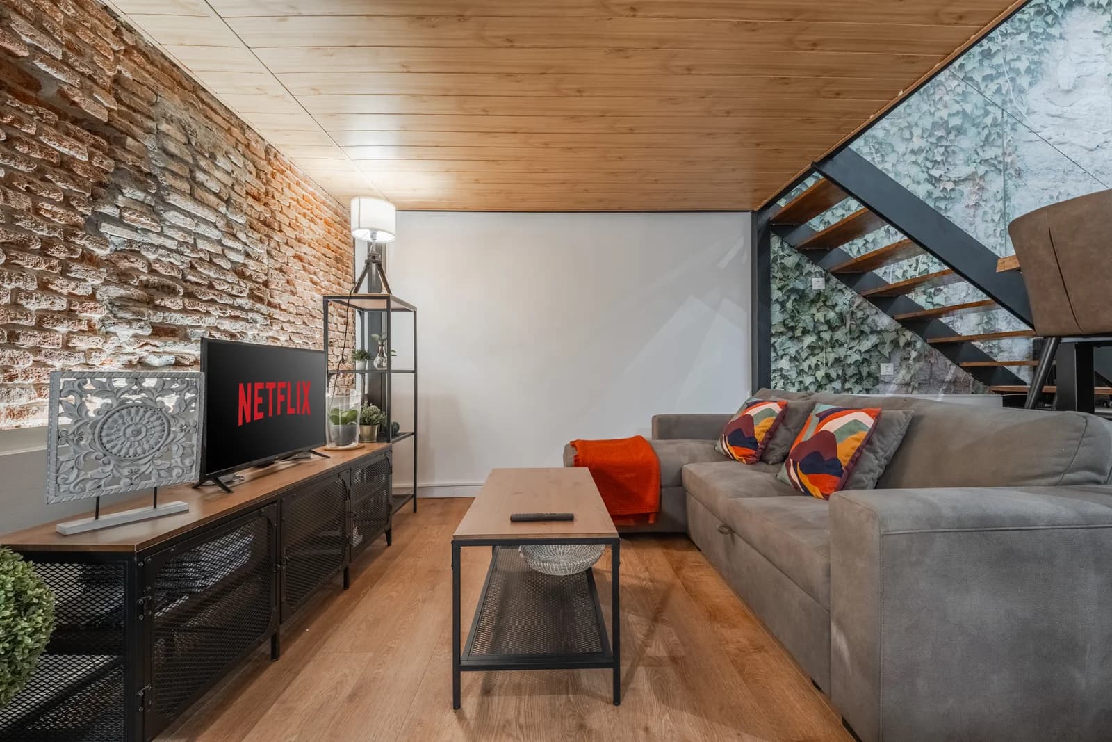 Grey sofa beside metal staircase and ivy backdrop, loft-style