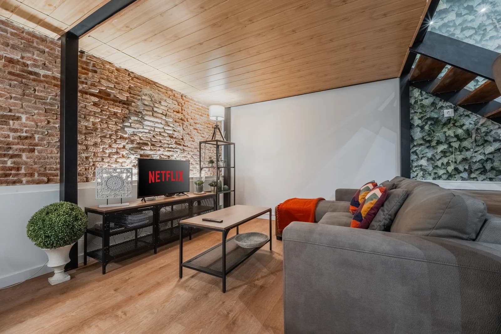 Cosy lounge with brick accent wall and floating wood ceiling