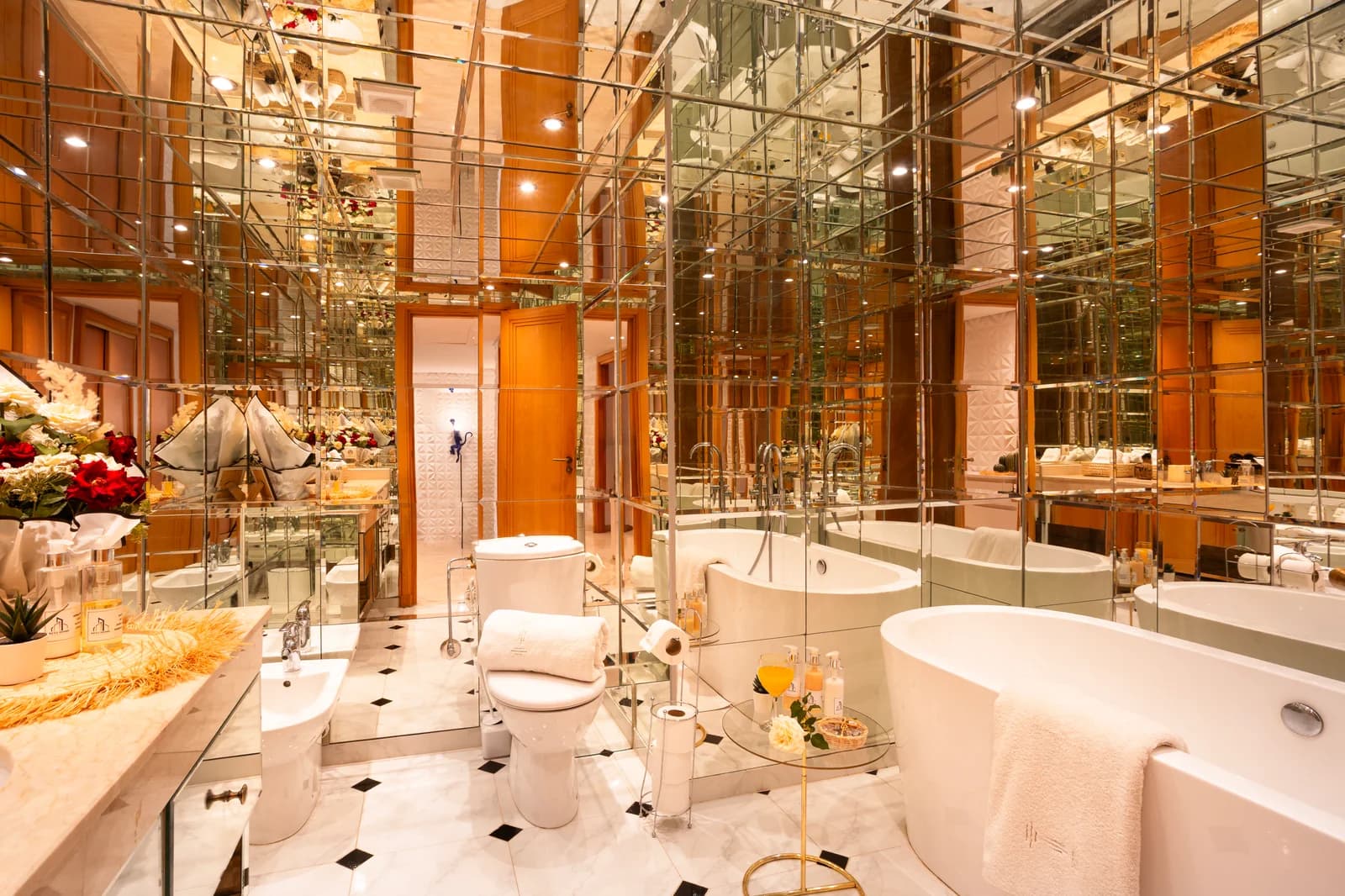 Mirrored marble bathroom with freestanding tub and floral arrangement